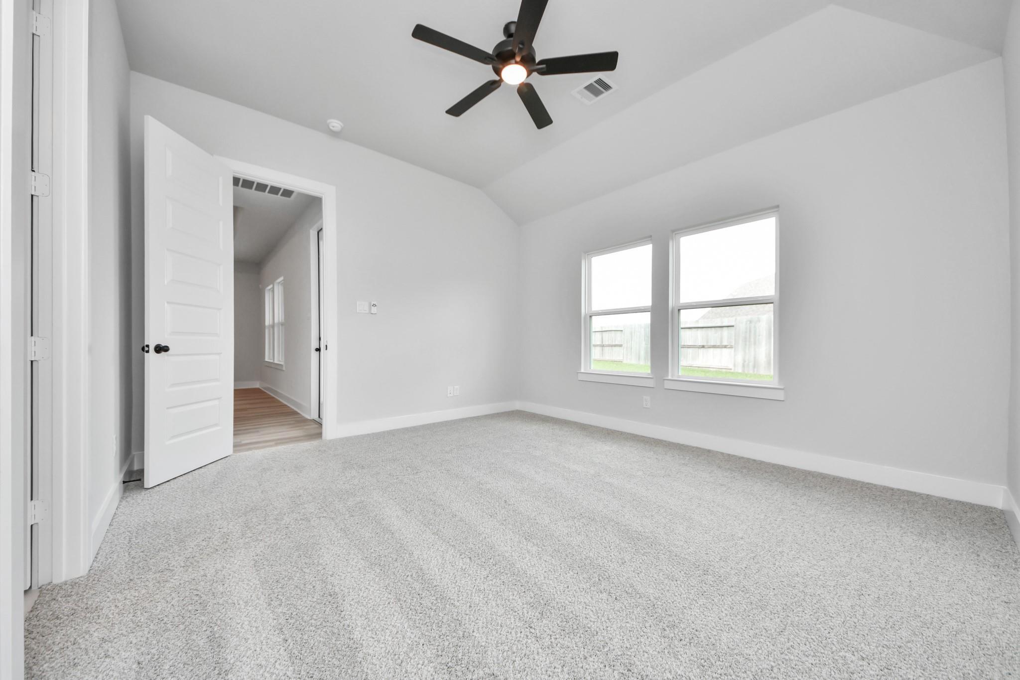 Bright, carpeted bedroom with ceiling fan in The Laguna C floor plan by Davidson Homes in Sunterra, Katy, Texas.