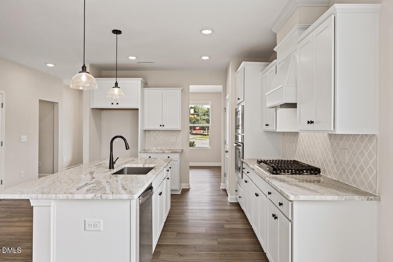 Modern kitchen with white cabinets, marble island, and gas cooktop in The Ash C floor plan at Woodland Crossing, Zebulon, NC.