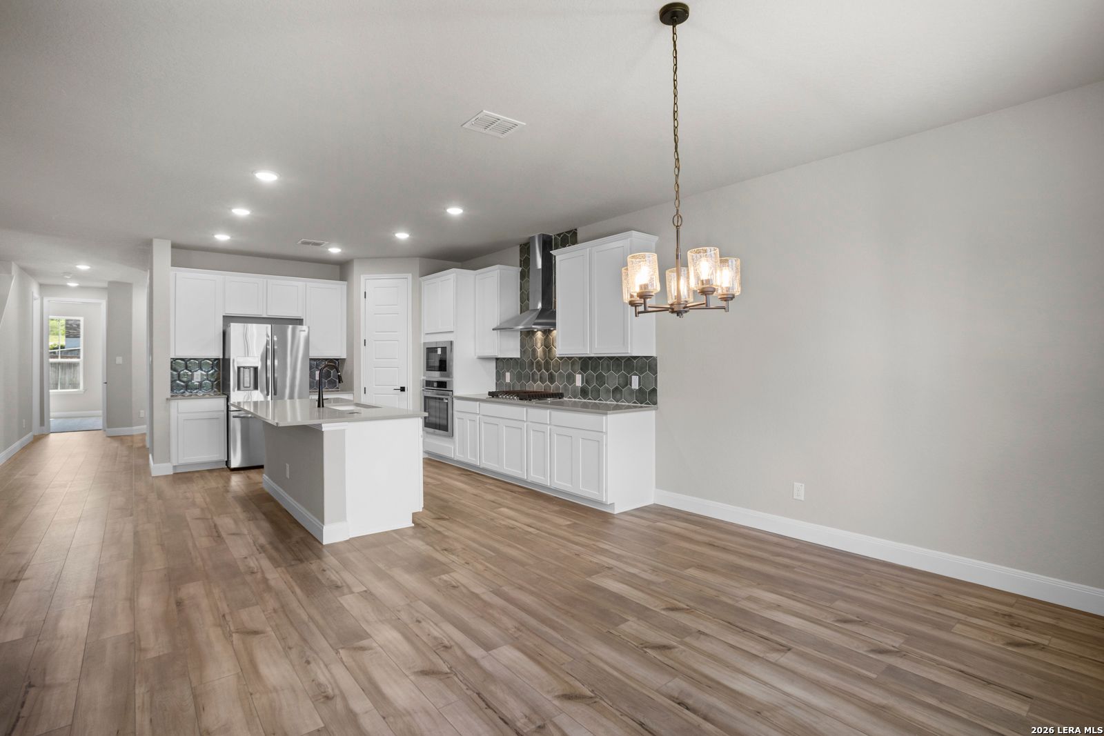 Modern kitchen with white cabinets, stainless appliances, and island in The Jennings G floor plan, Ladera, San Antonio.