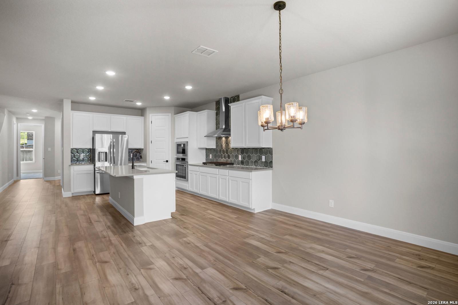 Modern kitchen with white cabinets, stainless appliances, and island in The Jennings G floor plan, Ladera, San Antonio.