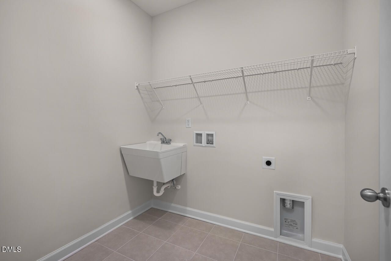 Functional laundry room with utility sink, wire shelving and washer/dryer hookups in Davidson Homes The Ash B, Lillington, NC