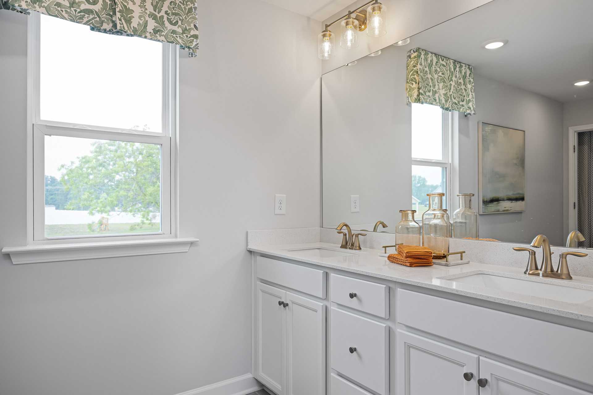 Spacious master bathroom at Beverly Place in Four Oaks NC with double vanity, white cabinets, large mirror, and window