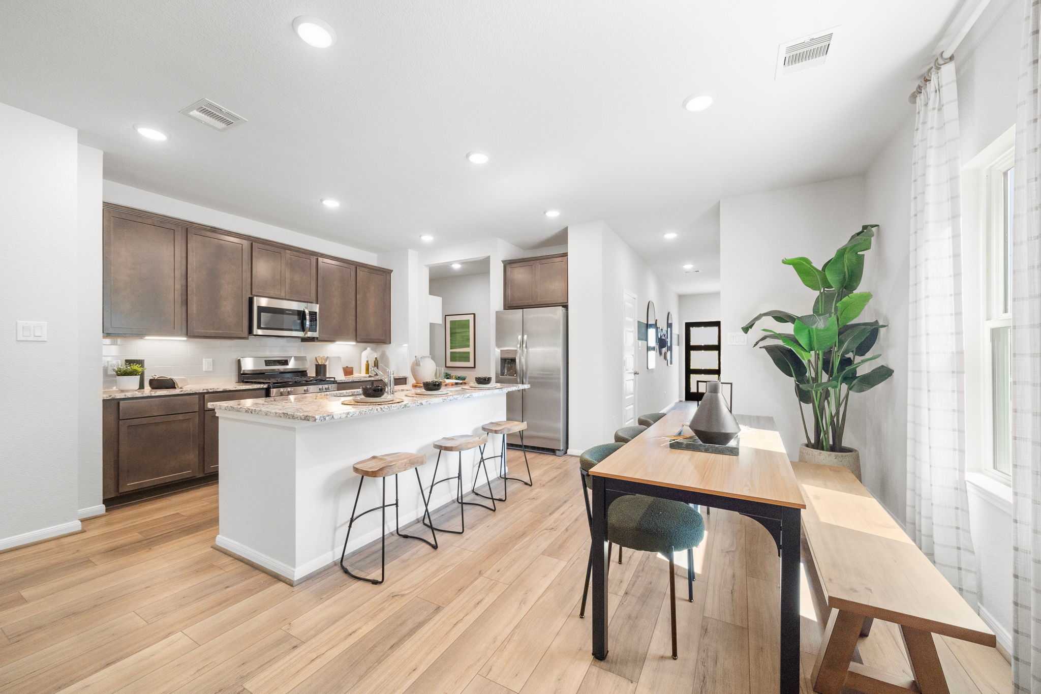 Modern kitchen at Caney Creek Place in Conroe TX with shaker cabinets stainless appliances white island bar seating and dining nook