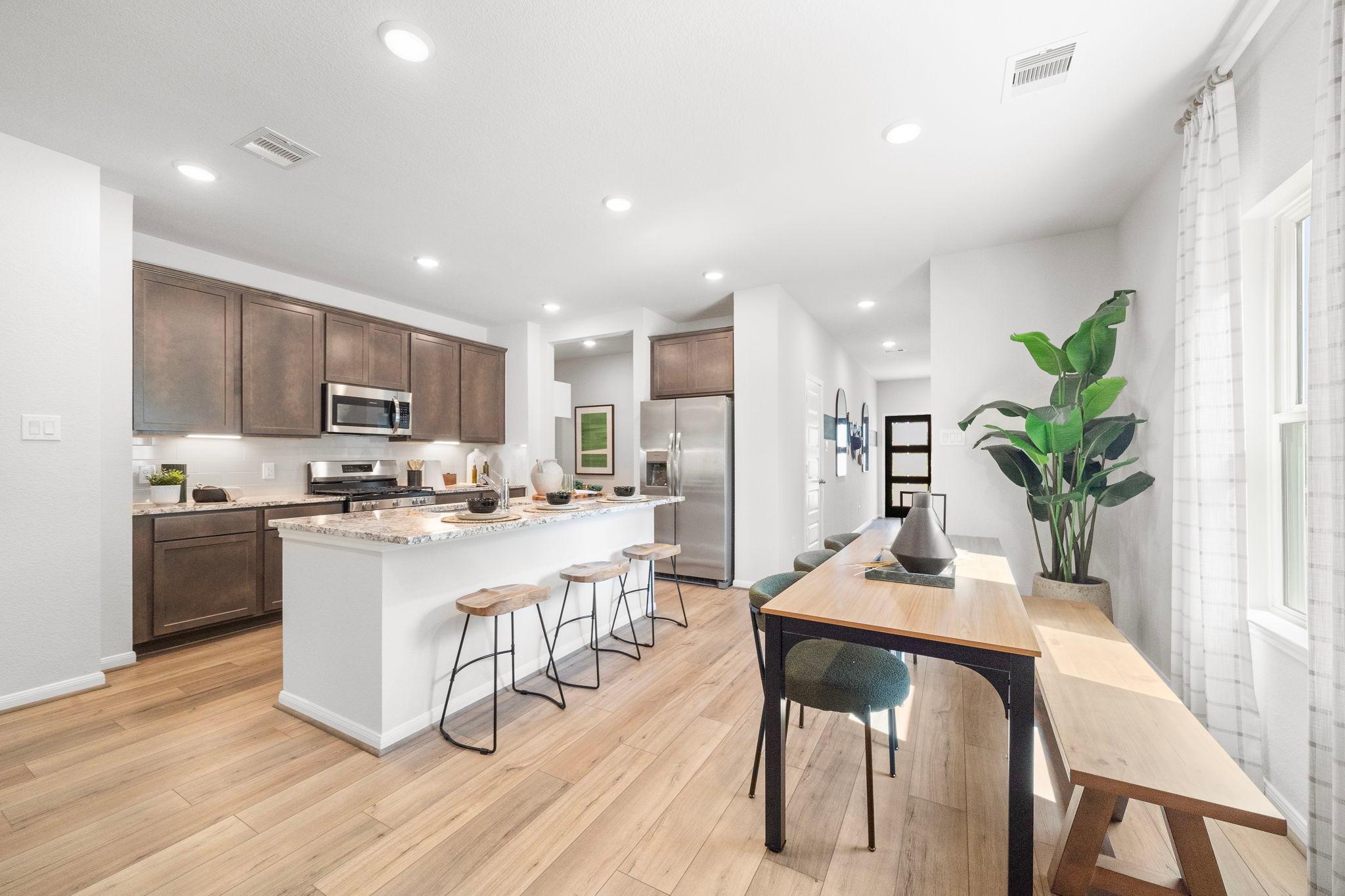 Modern kitchen at Caney Creek Place in Conroe TX with shaker cabinets stainless appliances white island bar seating and dining nook