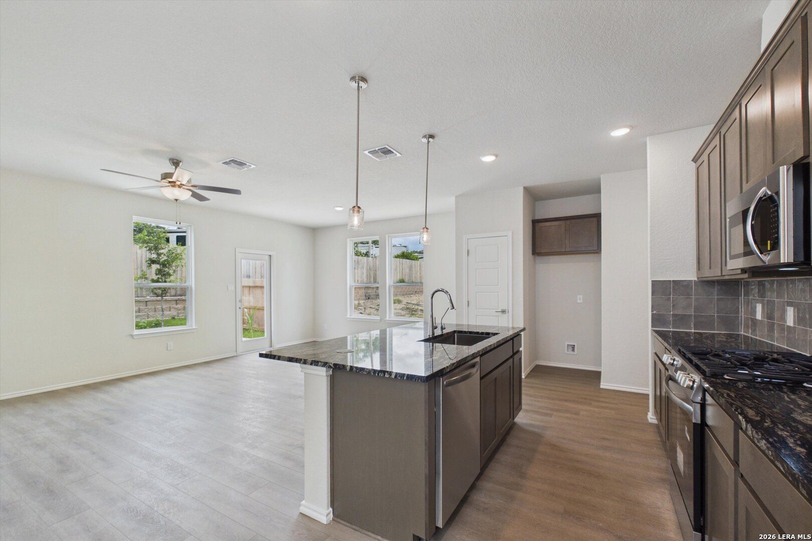 Open-concept kitchen with granite island and dark wood cabinets in The Charlotte B floor plan at Meadows at Oak Creek.