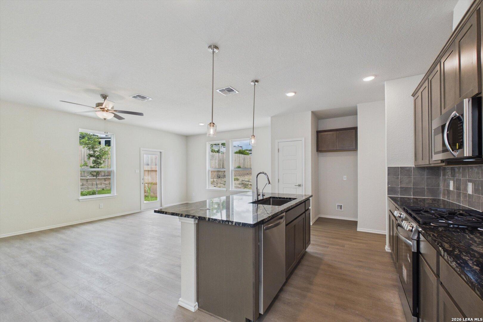 Open-concept kitchen with granite island and dark wood cabinets in The Charlotte B floor plan at Meadows at Oak Creek.