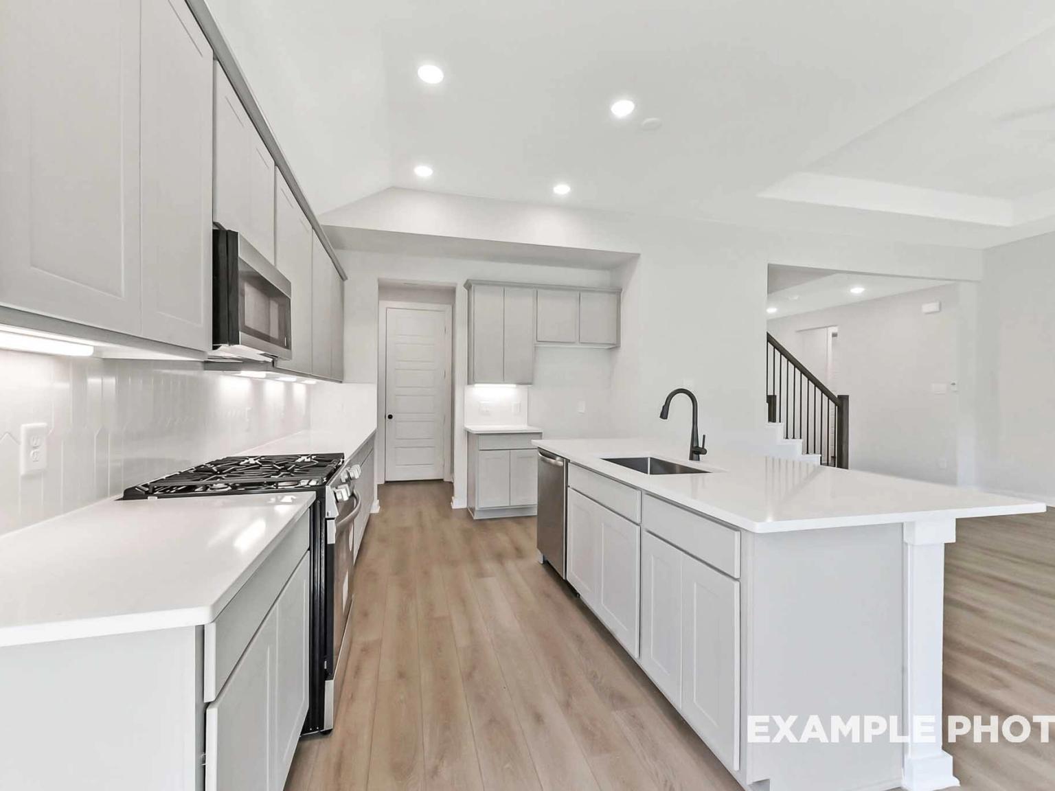 Modern kitchen with quartz countertops and light grey cabinets in The Sequoia C floor plan, Sundance Cove, Crosby, Texas.