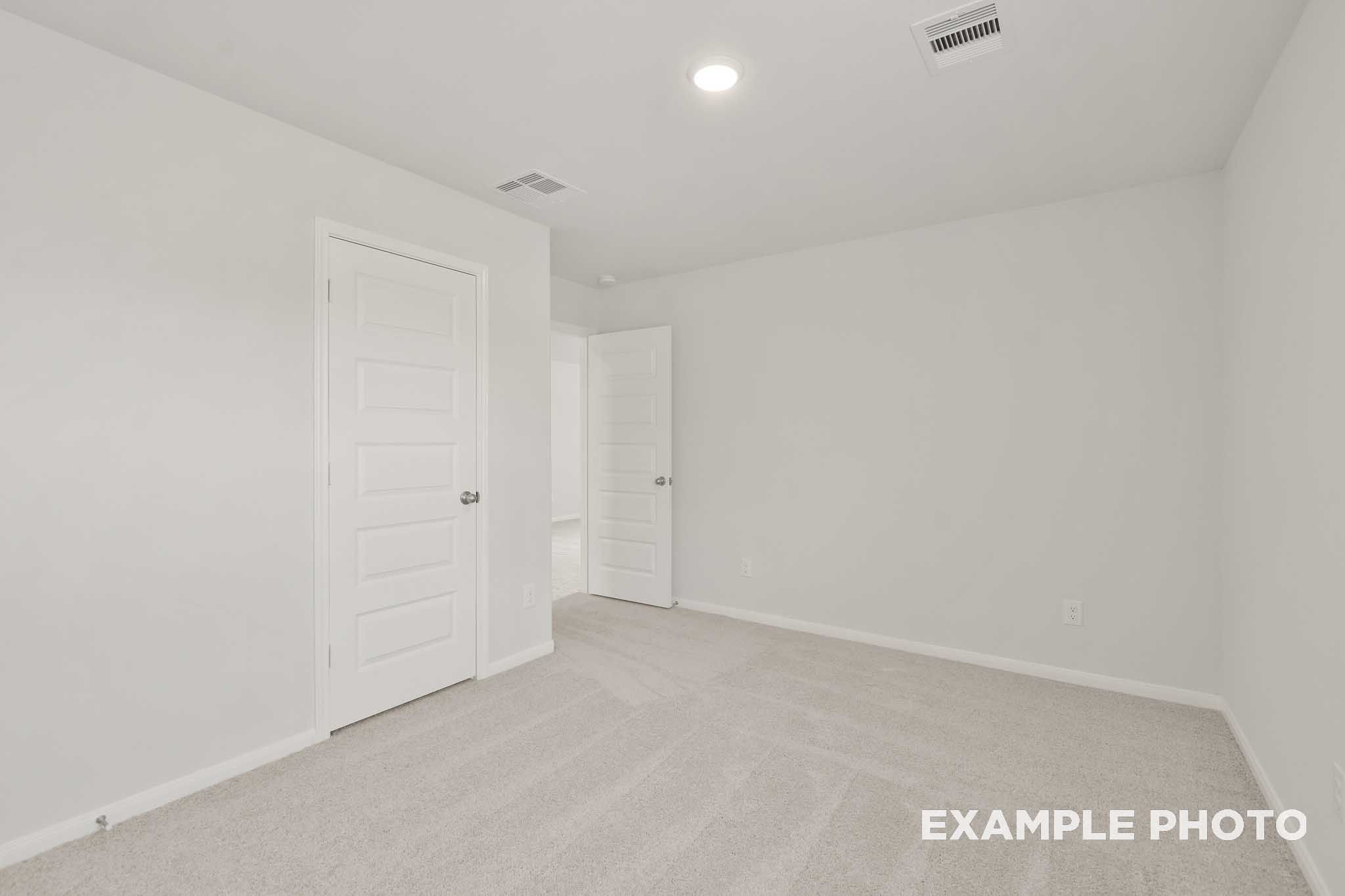 Spacious bedroom with neutral carpet and white doors in The Brazos by Davidson Homes, Beasley, Texas new home design