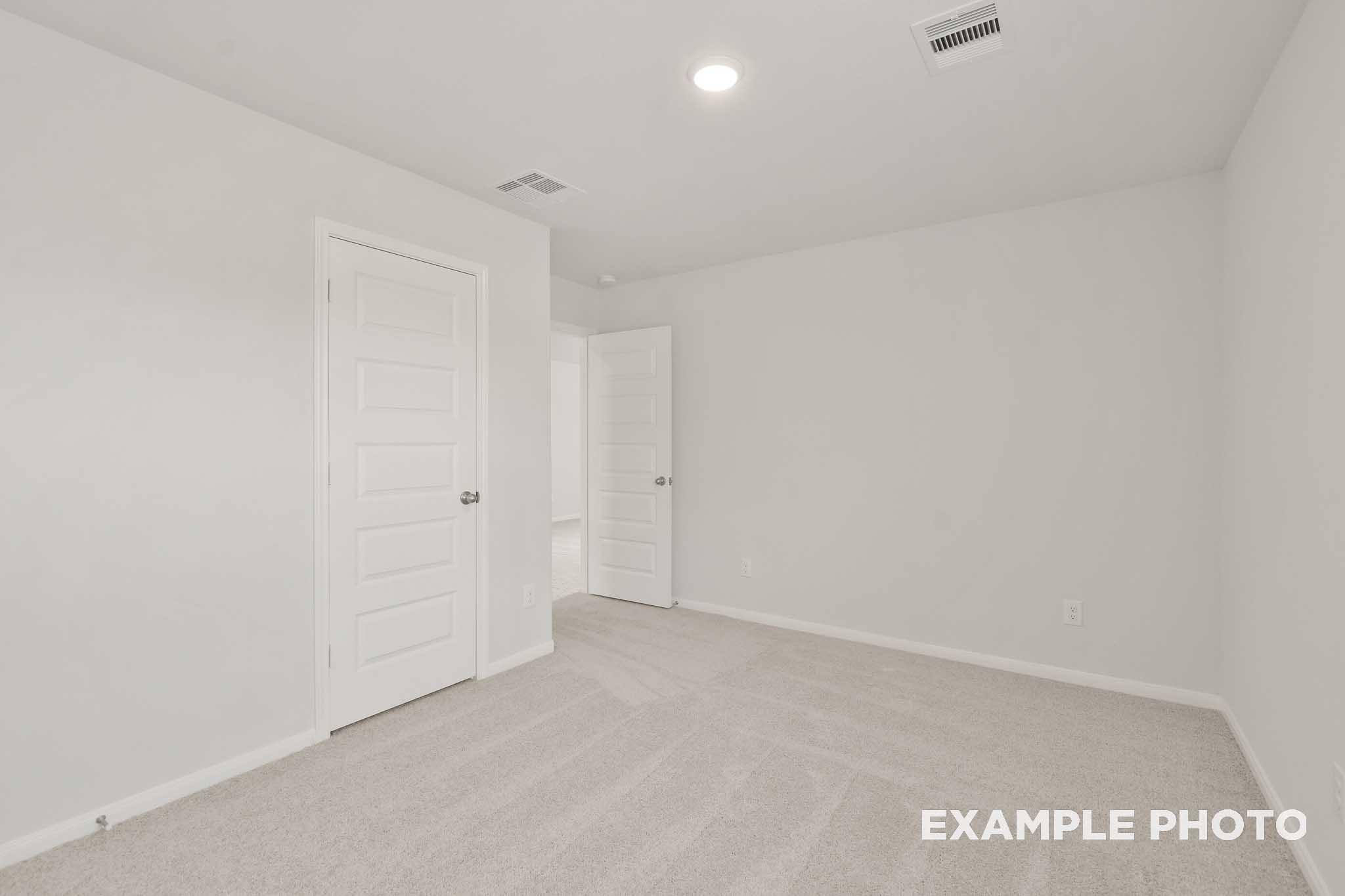 Spacious bedroom with neutral carpet and white doors in The Brazos by Davidson Homes, Beasley, Texas new home design