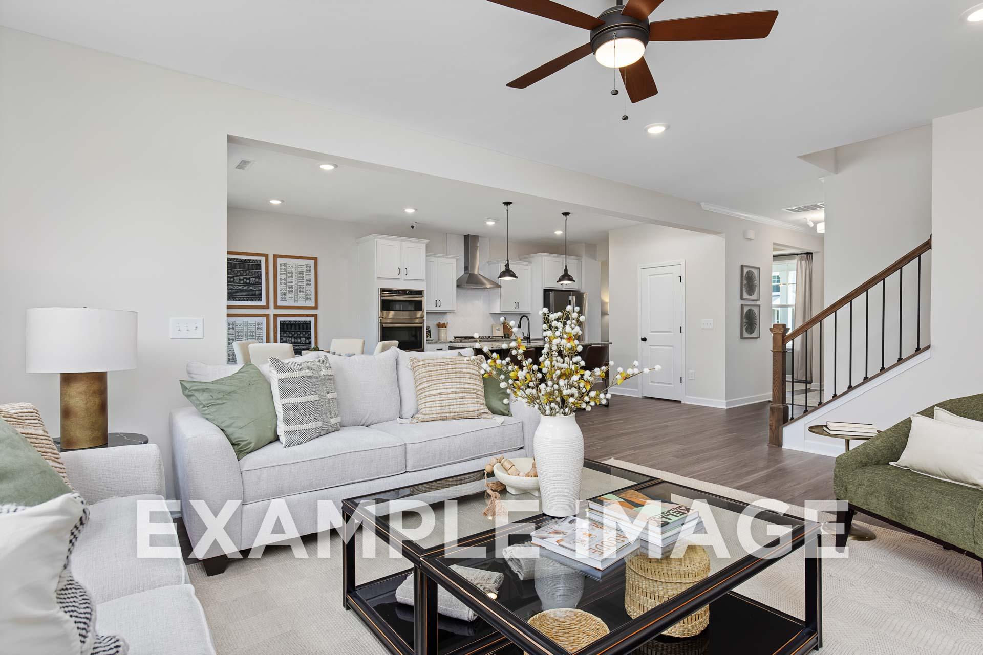 Spacious open-concept living room in The Willow E by Davidson Homes, white sectional sofa, modern kitchen island, hardwood floors