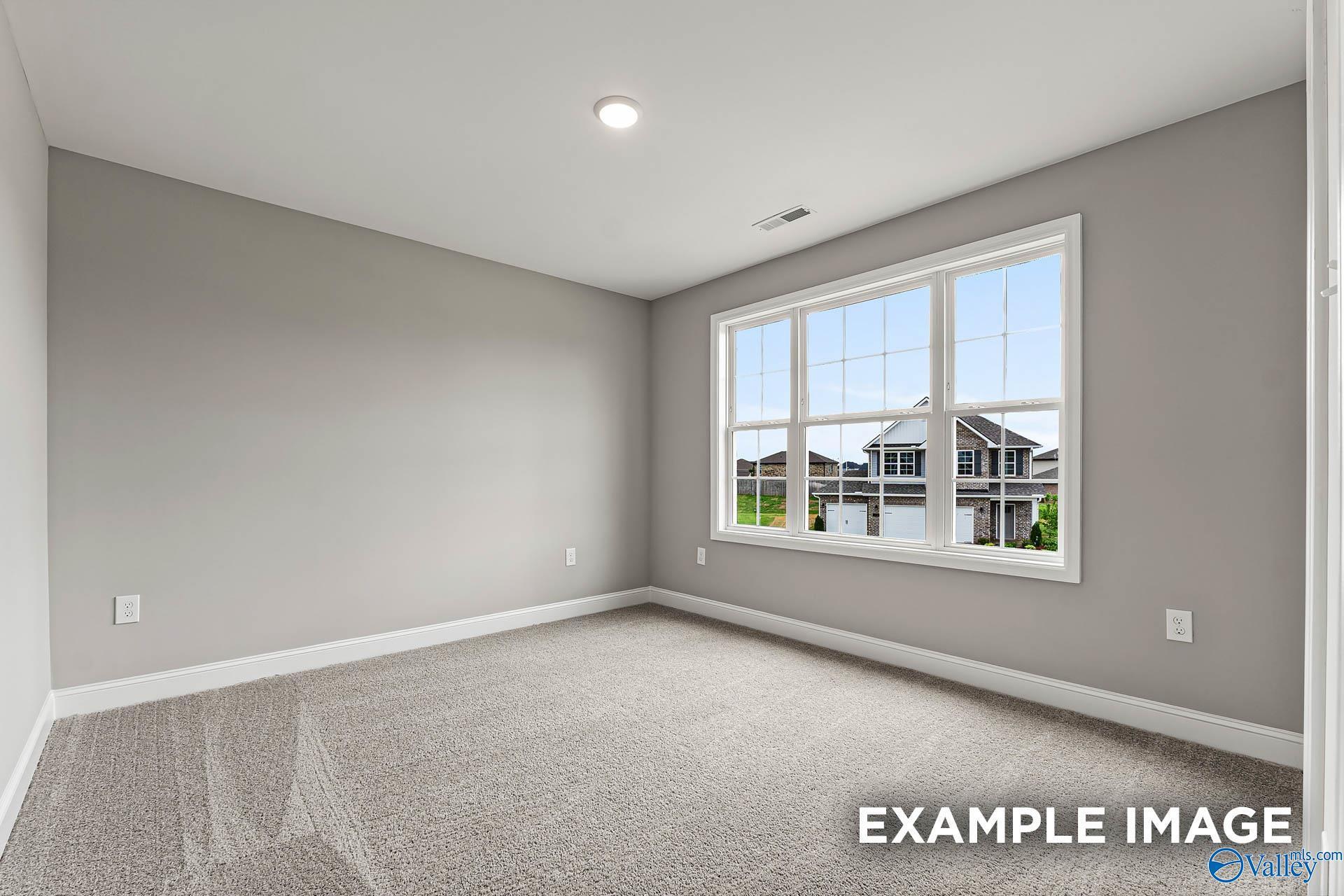 Empty bedroom with gray walls, neutral carpet, large window overlooking neighborhood in Davidson Homes Chelsea B, Toney Alabama