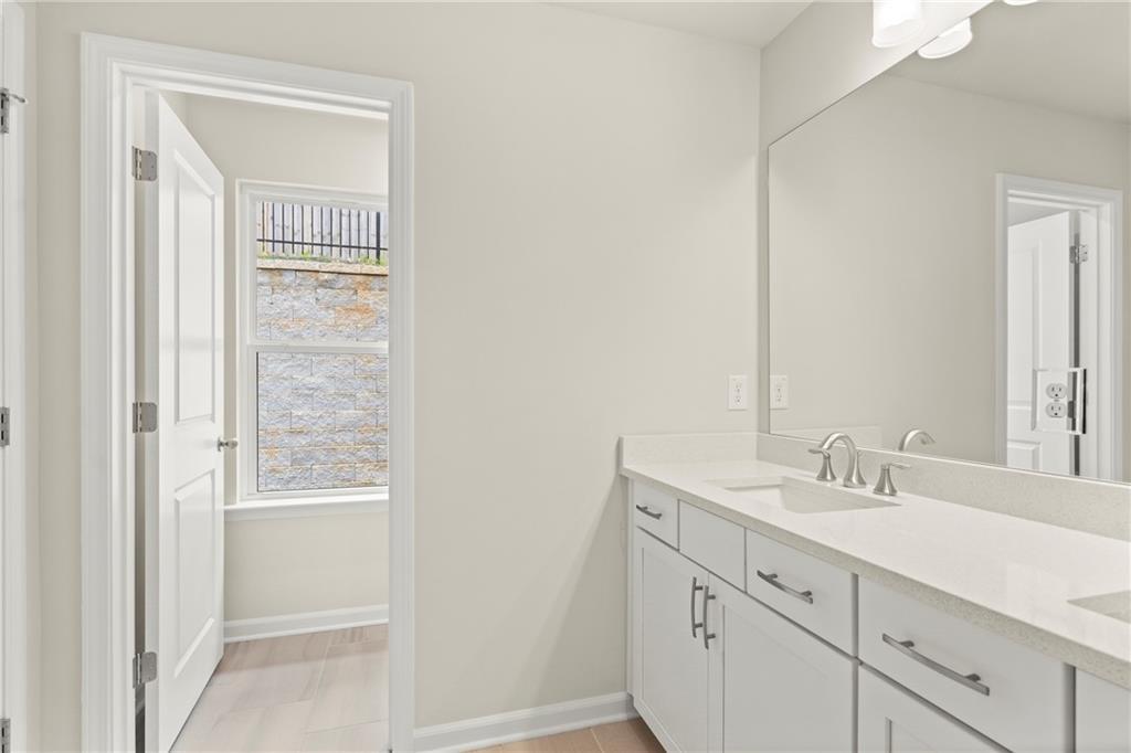 Elegant master bathroom with double vanity, quartz countertop, large mirror, and adjacent bedroom in Davidson Homes The Cary A, Kennesaw, GA