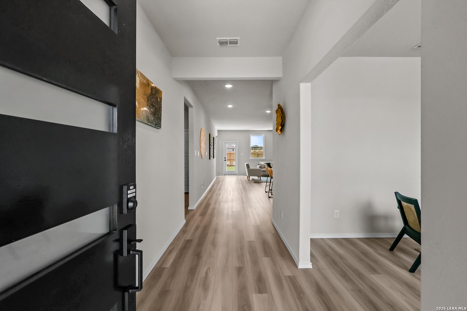Bright entryway with wood-look flooring leading to open living space in The Douglas C floor plan, Hannah Heights, Seguin.