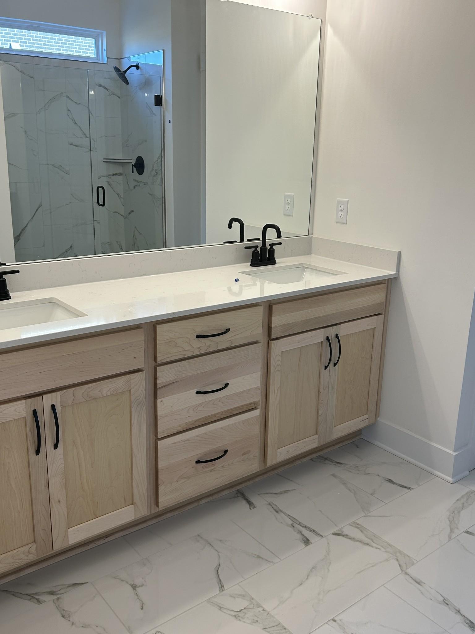 Modern master bathroom double vanity with light oak cabinets, quartz counters, and frameless glass shower in The Ridgeport E, Mt. Juliet, TN