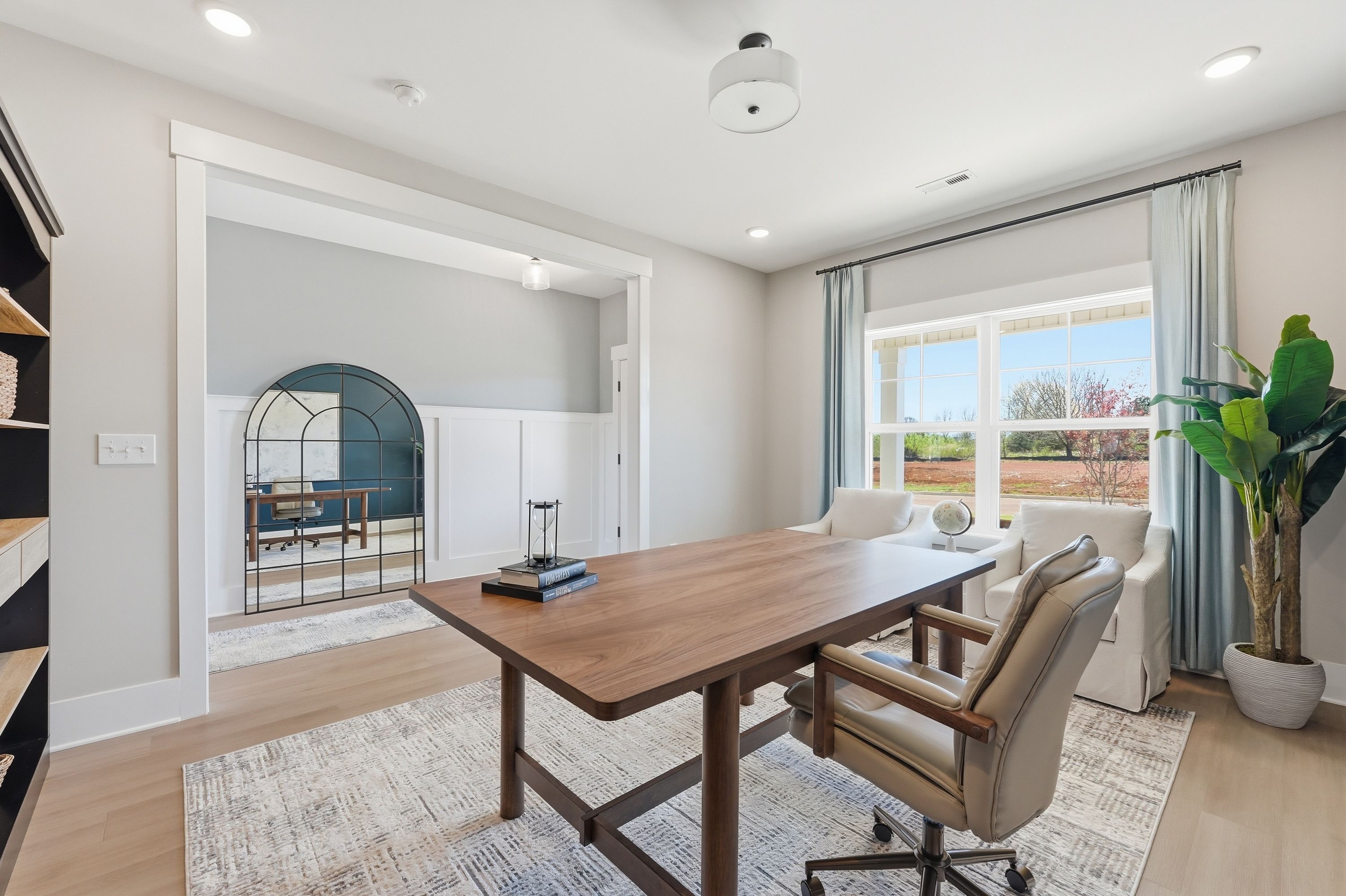 Spacious home office in Berry Cove, New Market AL with wooden desk, armchairs, bookshelves, and large windows