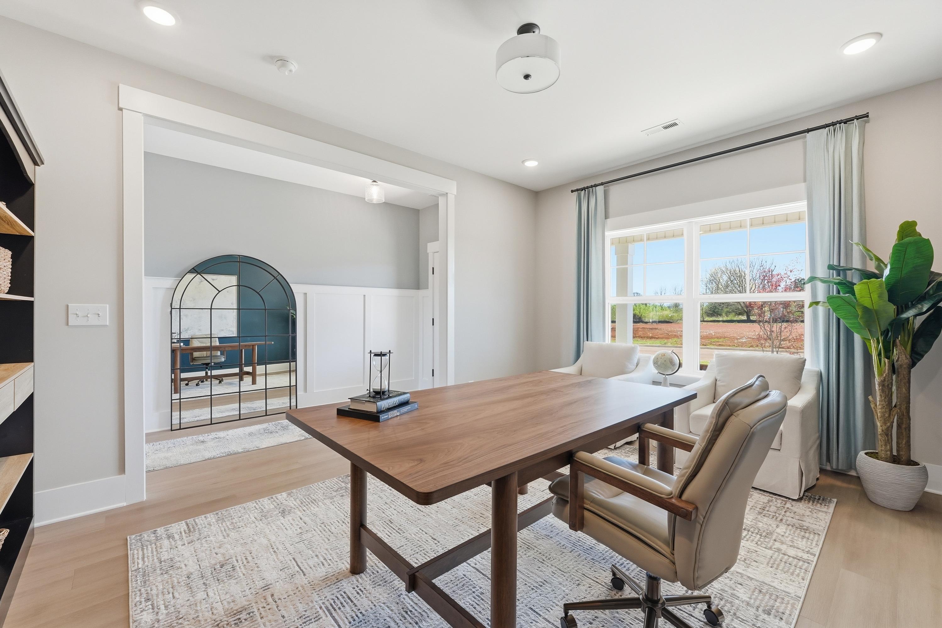 Spacious home office in Berry Cove, New Market AL with wooden desk, armchairs, bookshelves, and large windows