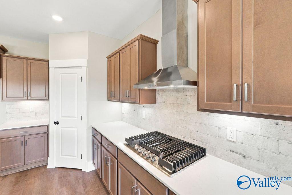Modern kitchen with wood cabinets, gas range, and vent hood in The Rockford floor plan at Cain Park, Hartselle, Alabama.