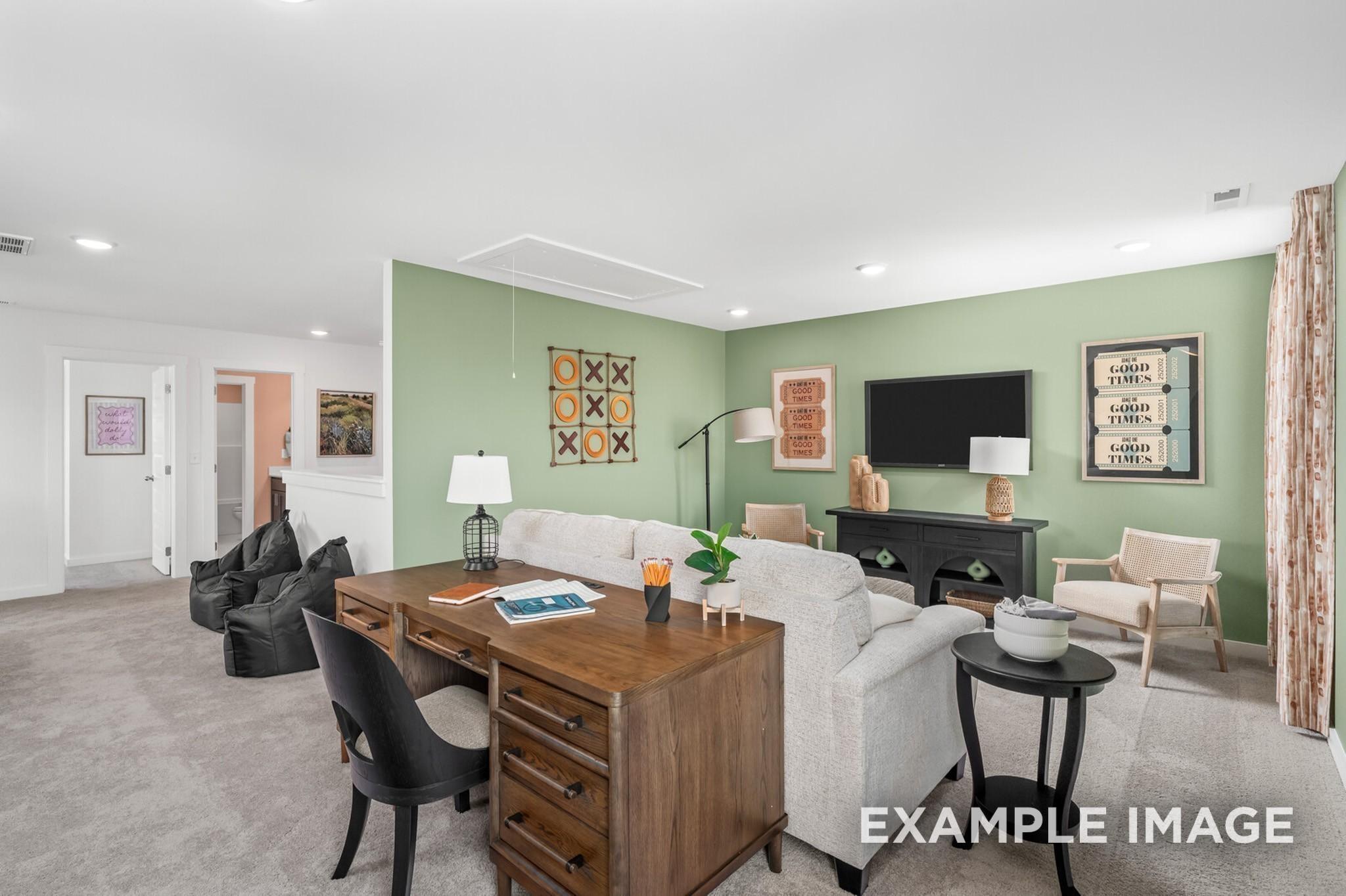 Spacious loft living area with home office desk, seating, and green accent wall in The Ash A plan at Woods Crossing, Gallatin.