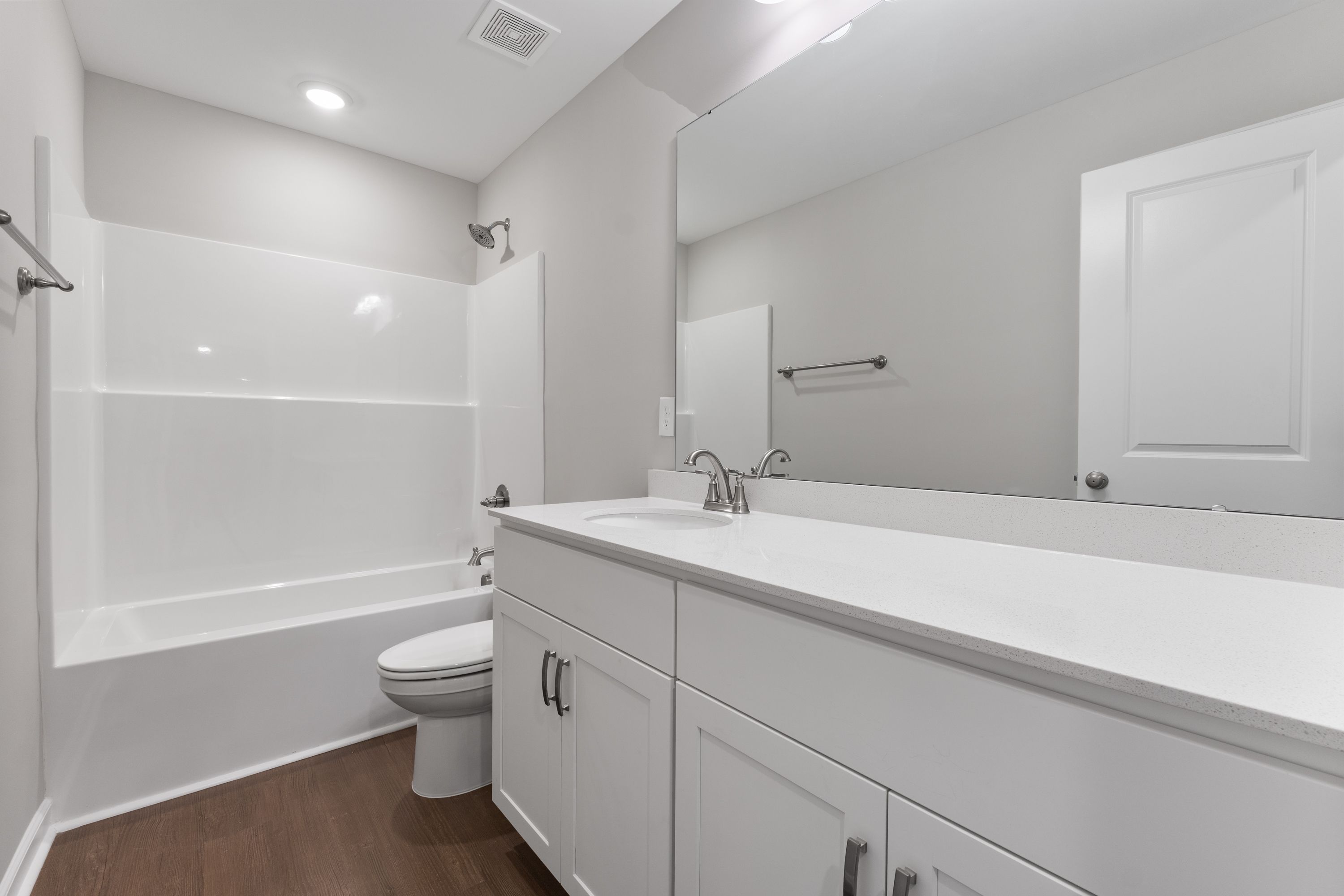 Spacious master bathroom in The Avalon E featuring white tub-shower combo, double vanity, and neutral tones