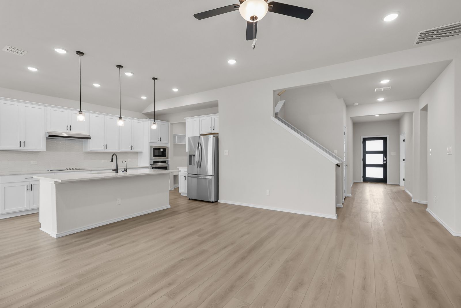 Open-concept kitchen in The Sequoia C featuring white cabinetry, a large island, and stainless steel appliances.