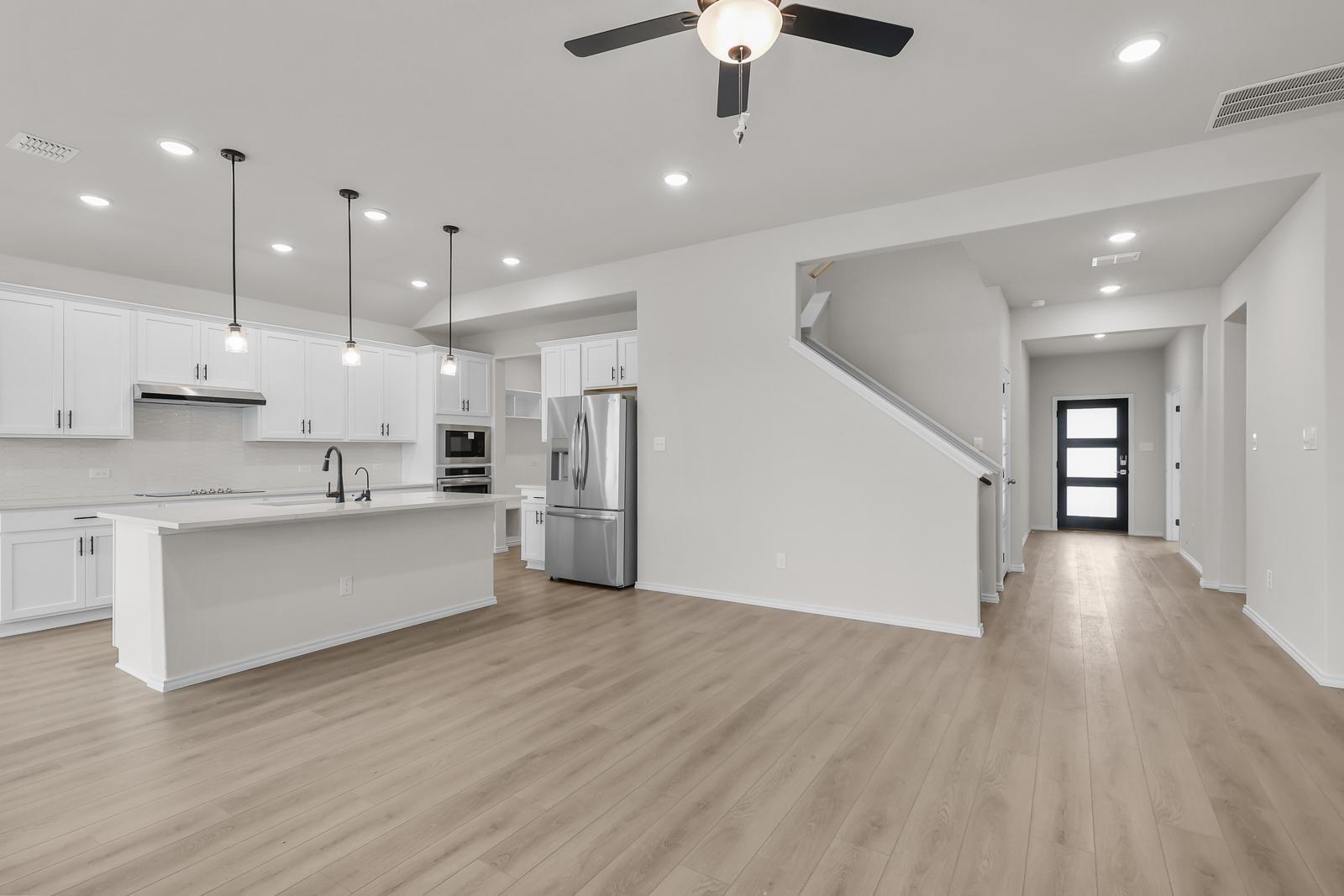 Open-concept kitchen in The Sequoia C featuring white cabinetry, a large island, and stainless steel appliances.