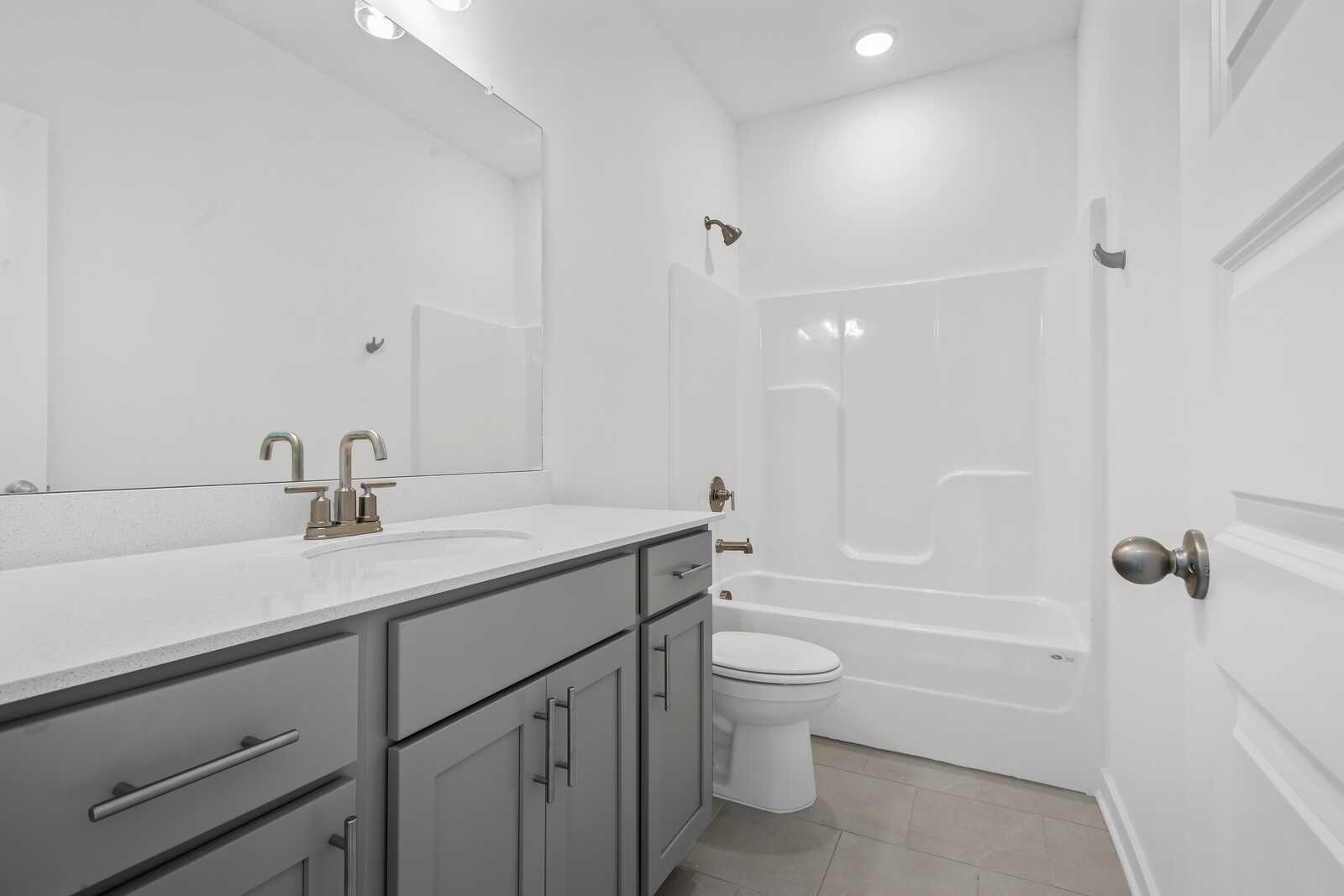 Modern bathroom in The Asheville home with gray vanity, white tub shower, and sleek fixtures