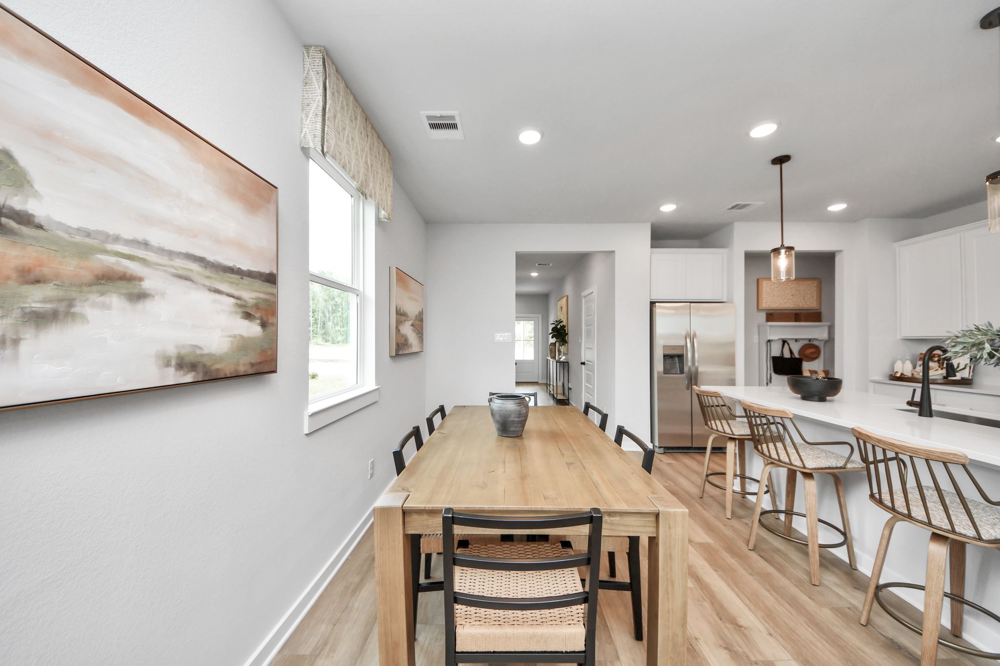 Dining area at Robins Landing in Houston, TX by Davidson Homes featuring a wooden table and kitchen island seating.