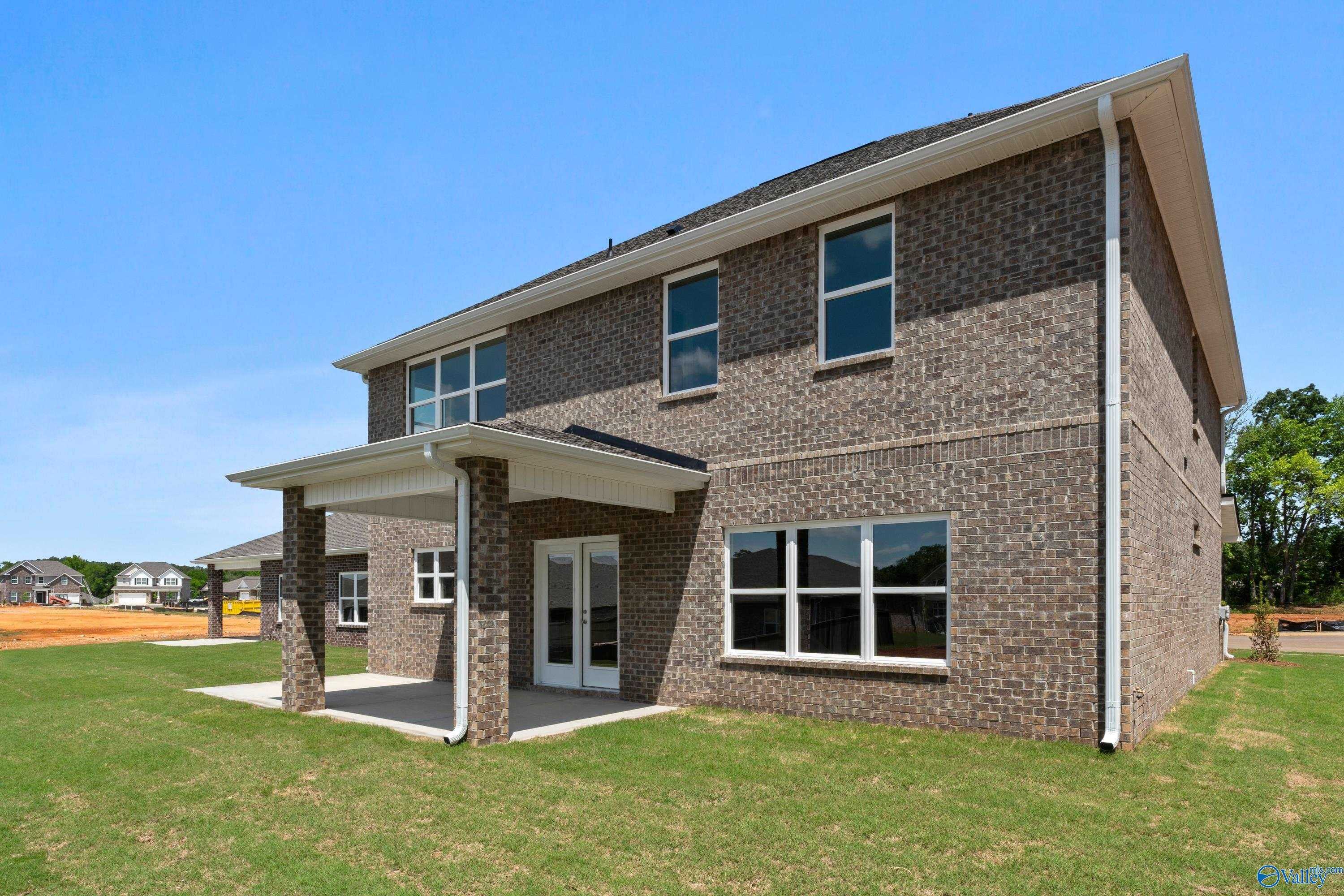 Two-story brick home with covered front porch, large windows, and lush lawn in Creek Grove, New Market, Alabama