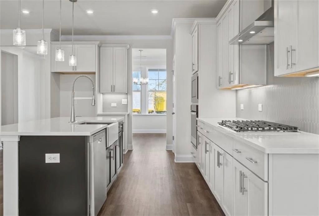 Modern kitchen with white cabinetry, quartz countertops, and a large island in The Ash C floor plan at Wehunt Meadows.