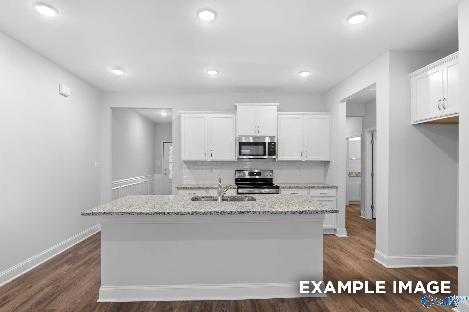 Bright open-concept kitchen with granite island, white cabinets, stainless appliances in Davidson Homes The Cumberland, Decatur AL