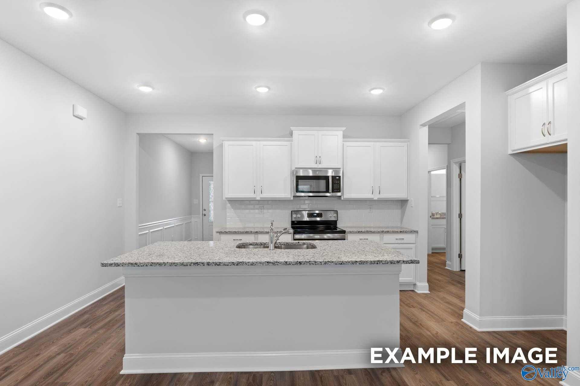 Bright open-concept kitchen with granite island, white cabinets, stainless appliances in Davidson Homes The Cumberland, Decatur AL