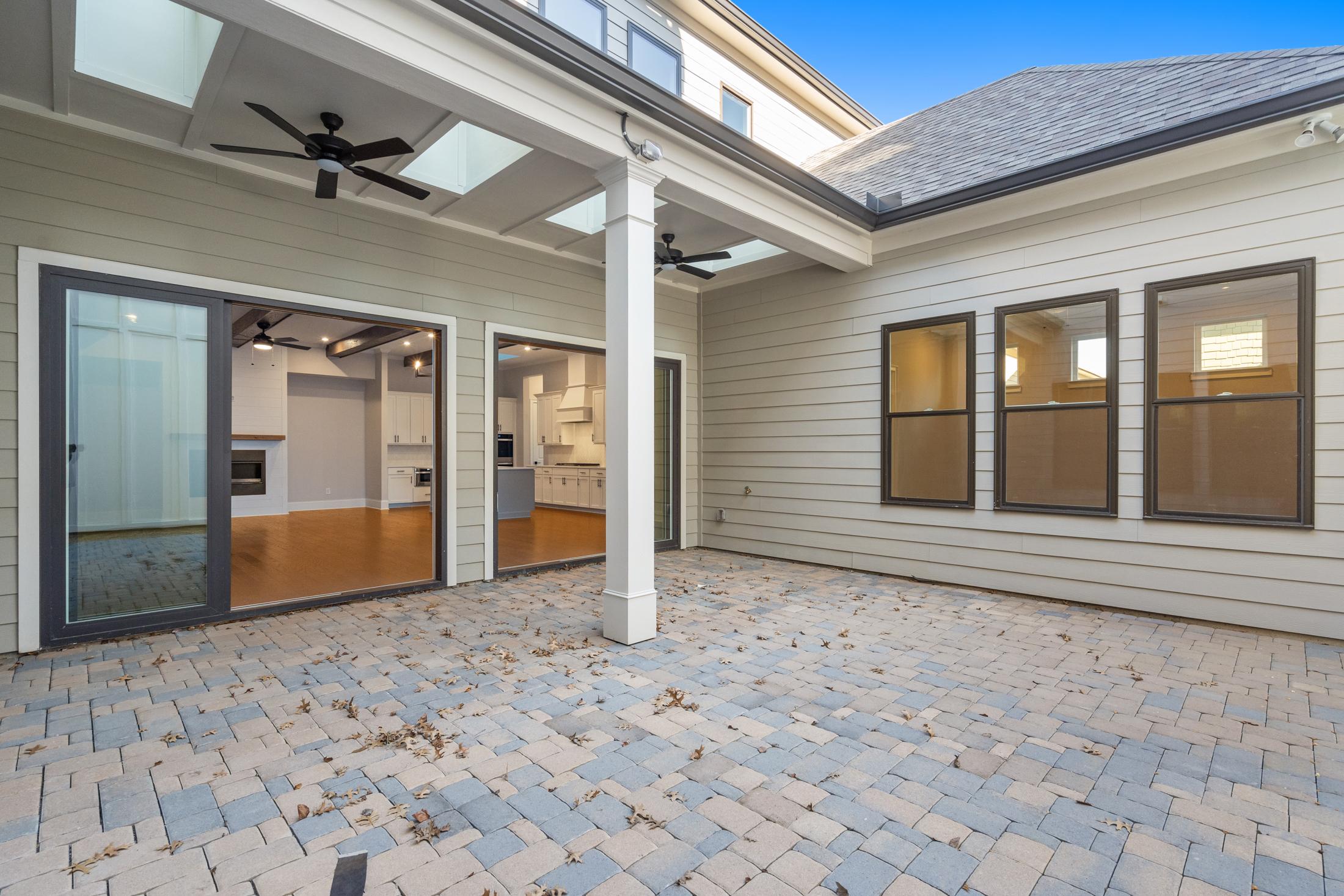 Covered patio of The Seaside home design with ceiling fans, skylights, large glass doors to paver deck and kitchen view