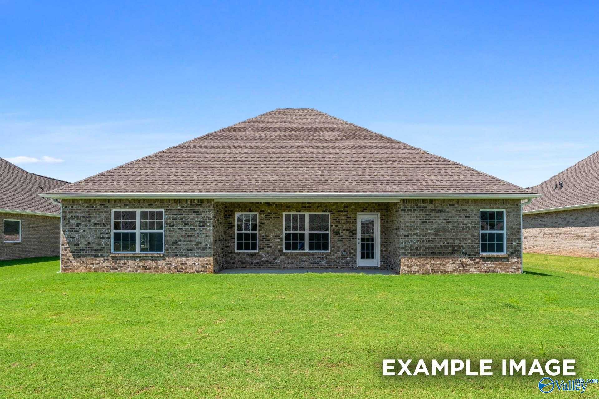 Brick single-story home rear facade with covered patio, large windows, French doors, and lush green lawn in Pikes Ridge, Meridianville, Alabama