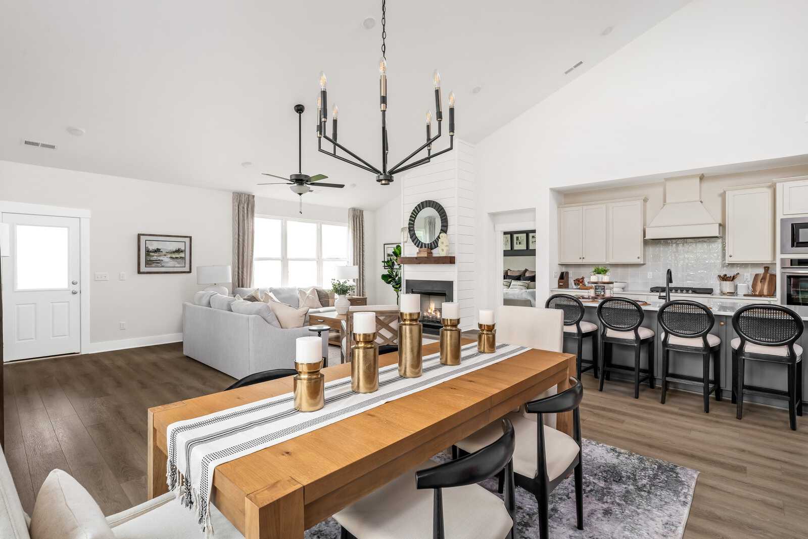 Open-concept living and dining area in Woods Crossing home, Gallatin TN with hardwood floors, chandelier, fireplace and bar seating