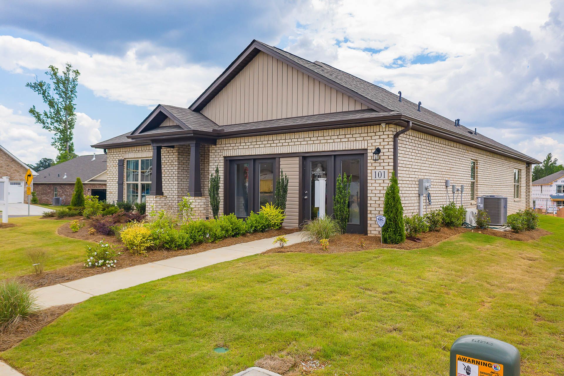 Contemporary ranch-style home exterior at Heritage Heights in Madison, Alabama with beige siding, brick accents, and landscaped yard