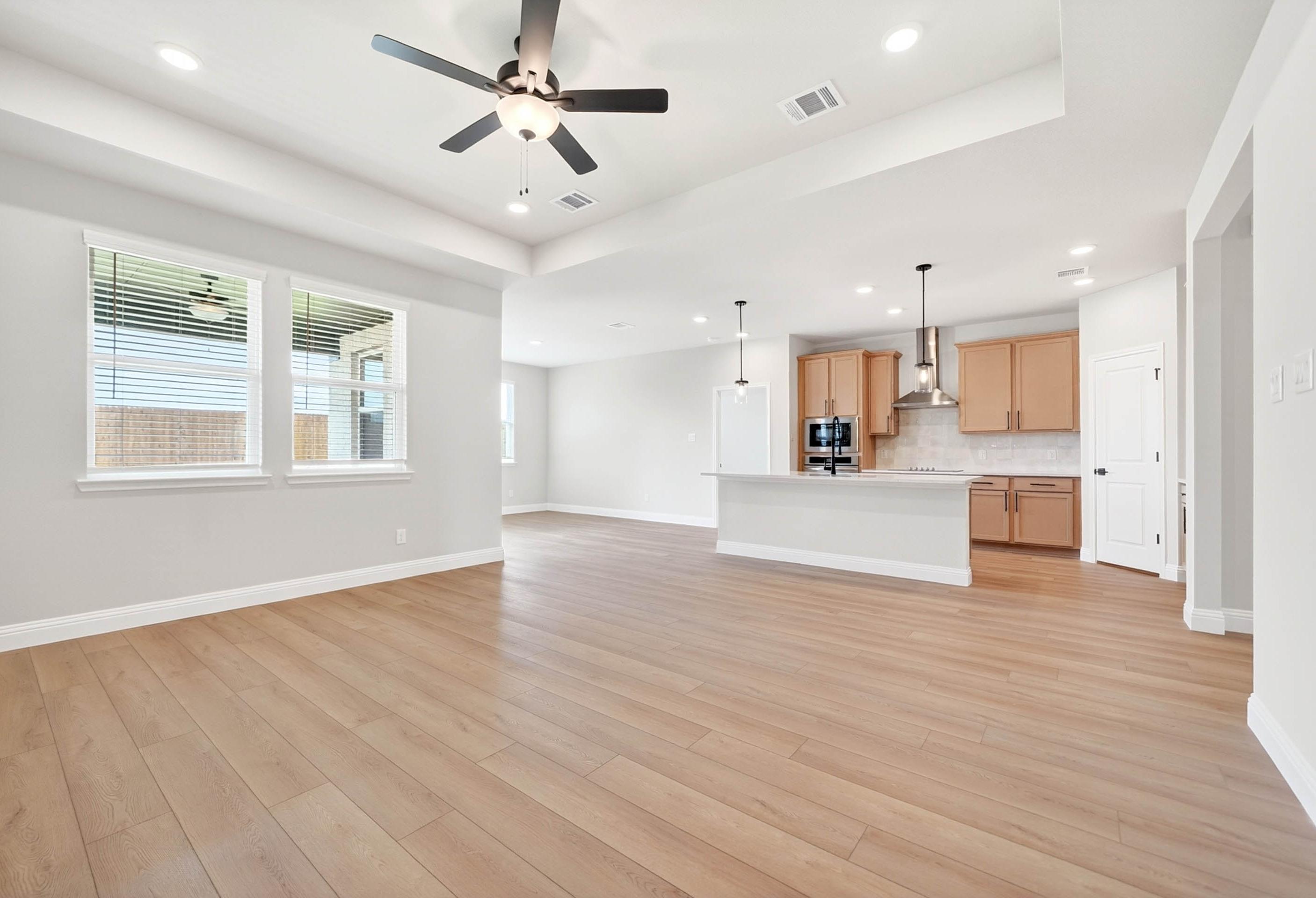 Open-concept living and kitchen area in The Holly C by Davidson Homes, featuring light wood flooring and modern cabinetry.