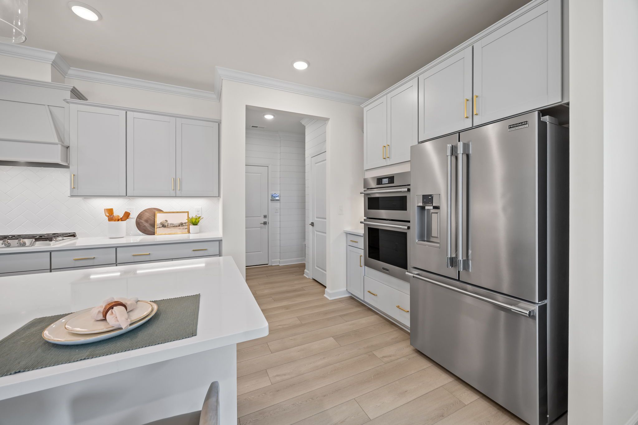 Modern kitchen at Springvale South in Fuquay-Varina with white cabinets, stainless steel appliances, and quartz island.