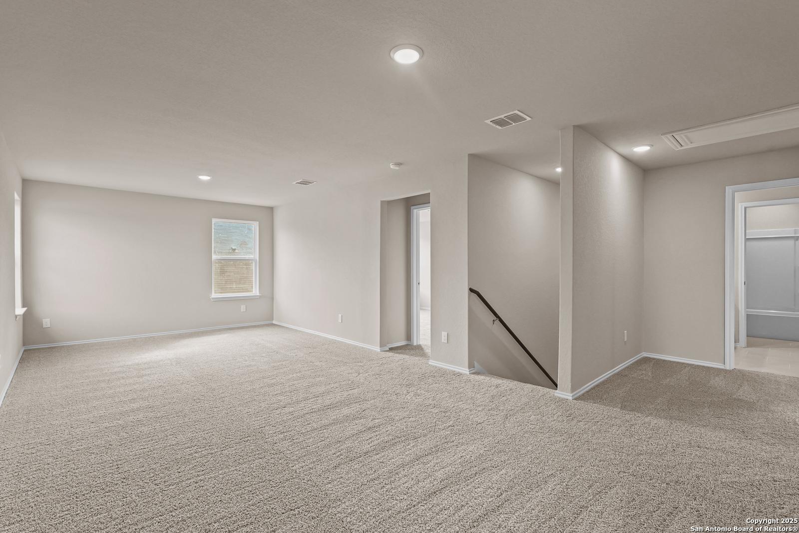 Spacious upstairs bonus room with beige carpet, recessed lights, and stairs in 4-bedroom Davidson Homes The Douglas G, San Antonio, TX