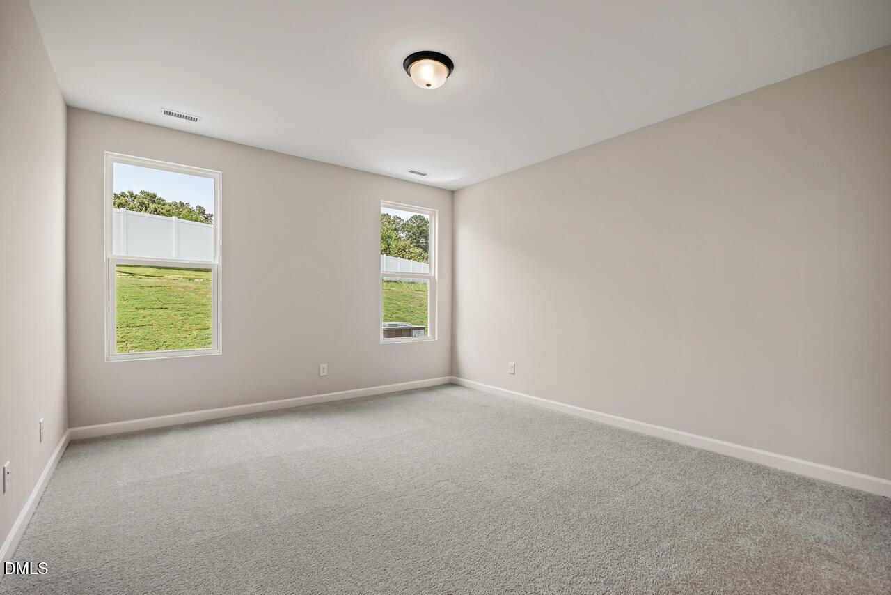 Spacious, neutral-toned bedroom with plush carpet in The Ash C floor plan at Woodland Crossing, Zebulon, North Carolina.