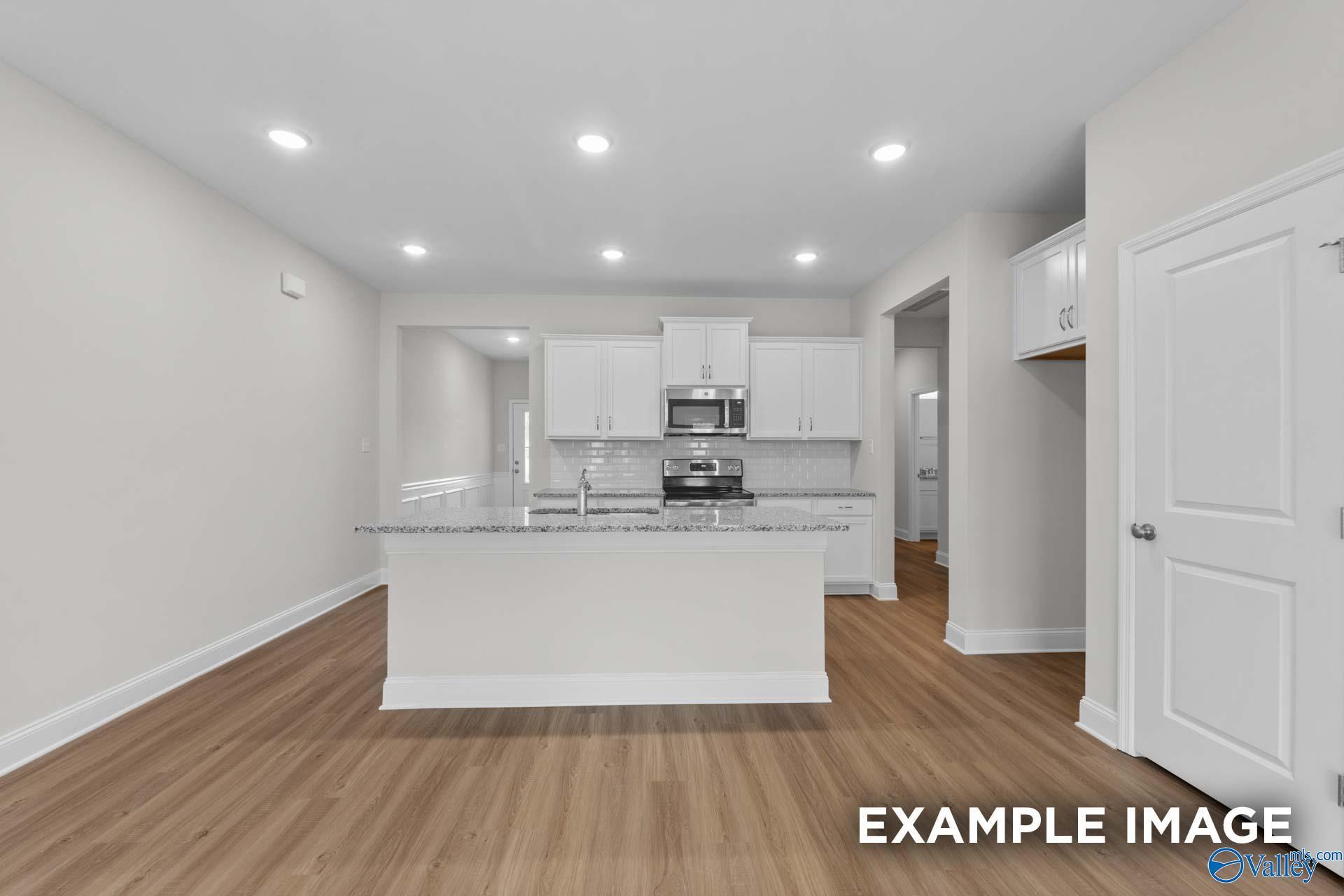 Modern open-concept kitchen featuring white shaker cabinets, granite island, stainless steel appliances in Davidson Homes The Cumberland D, Decatur, AL