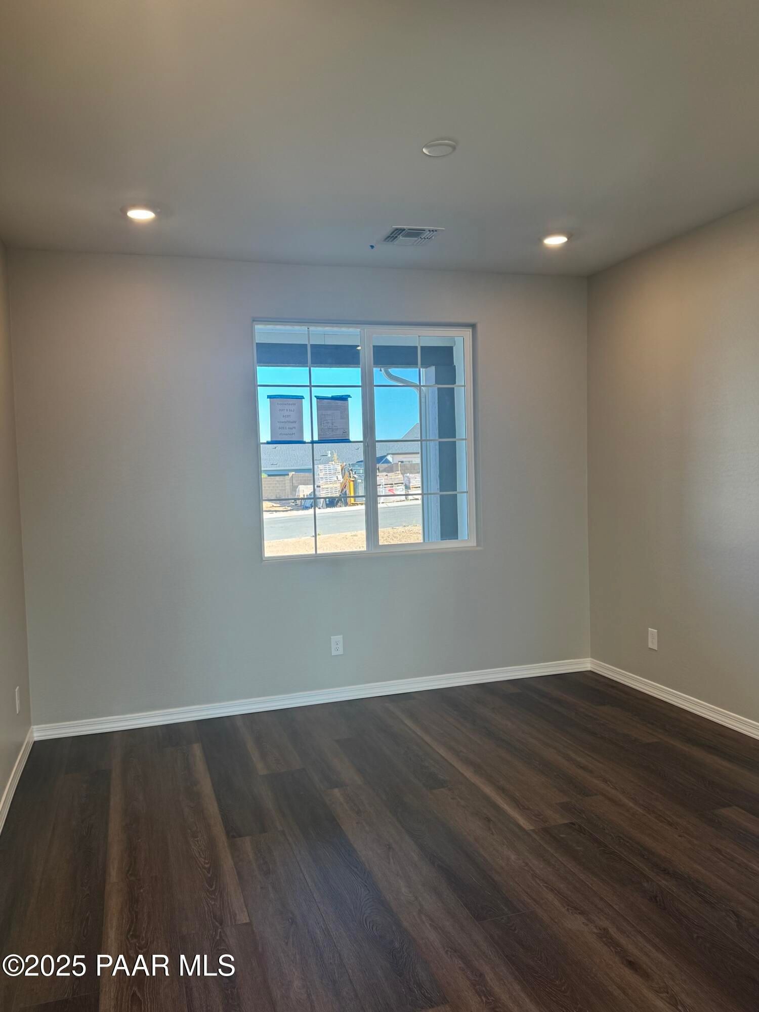 Bright empty bedroom with large window, neutral beige walls, luxury vinyl plank flooring in Davidson Homes The Monarch E, Prescott AZ