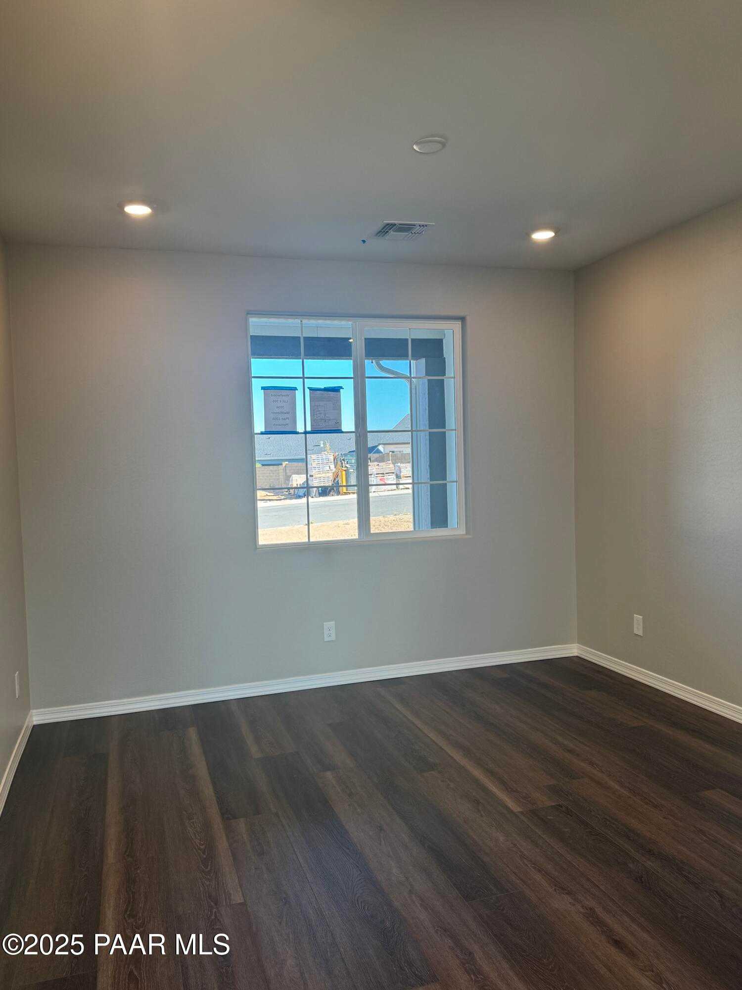 Bright empty bedroom with large window, neutral beige walls, luxury vinyl plank flooring in Davidson Homes The Monarch E, Prescott AZ