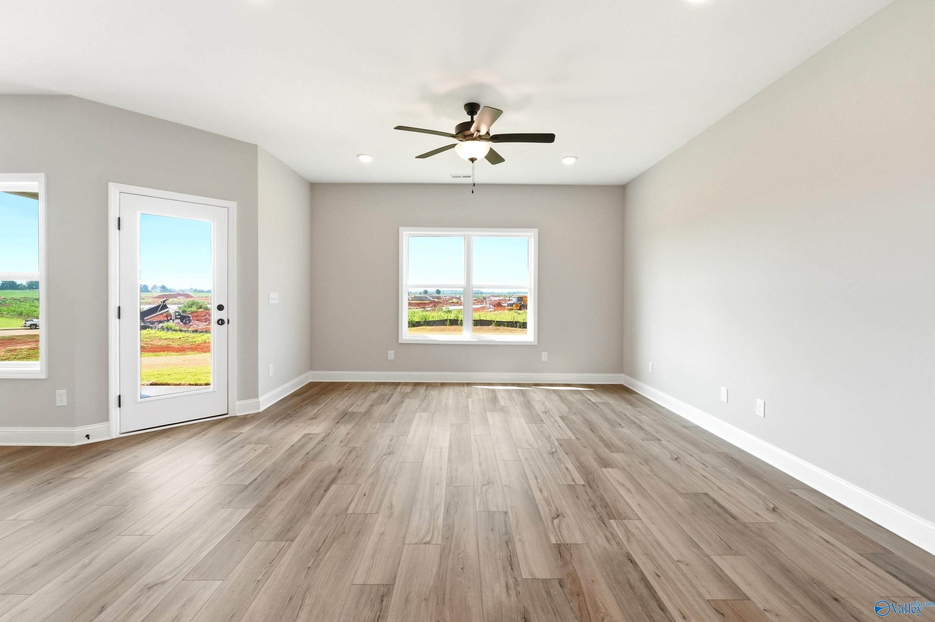 Spacious living room with wood-look flooring and ceiling fan in The Daphne D floor plan at Creekside, Harvest, Alabama.