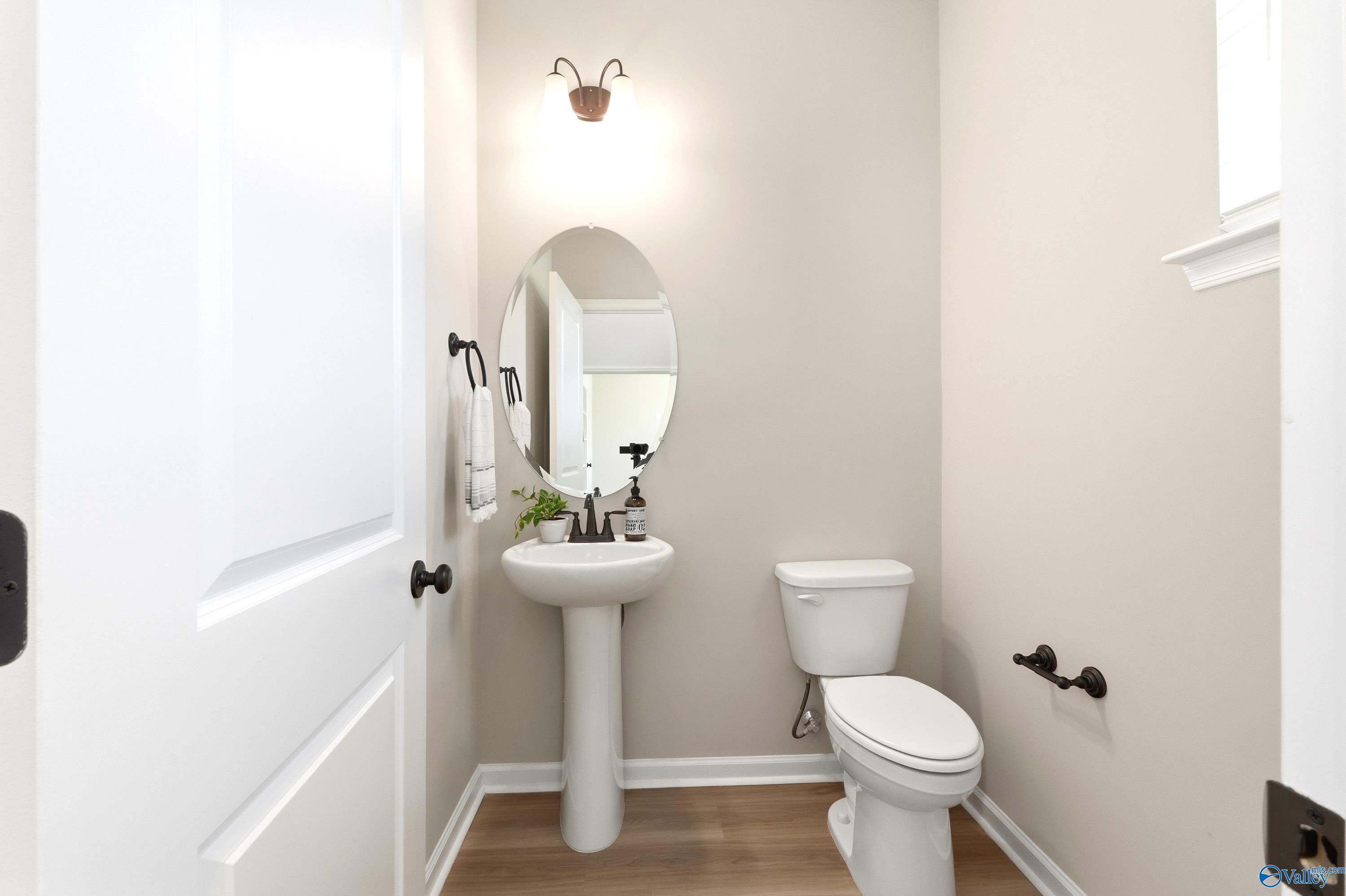 Half bathroom with pedestal sink, oval mirror, and neutral walls in The Dorado floor plan at Riverton Preserve, Huntsville.