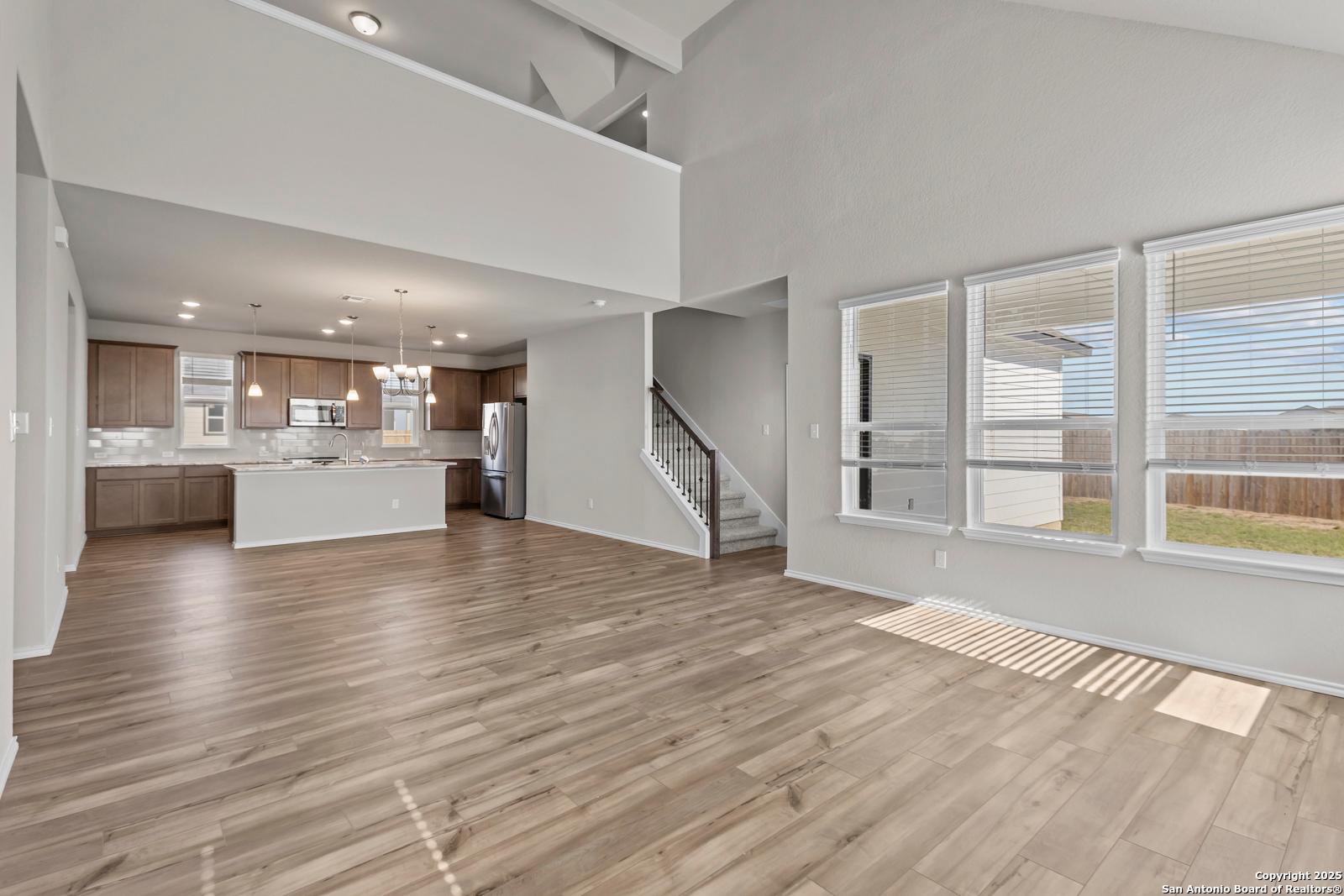 Open-concept kitchen and living area with wood floors, stainless appliances, and large windows in 3-bedroom Davidson Homes Collin B, Seguin, TX