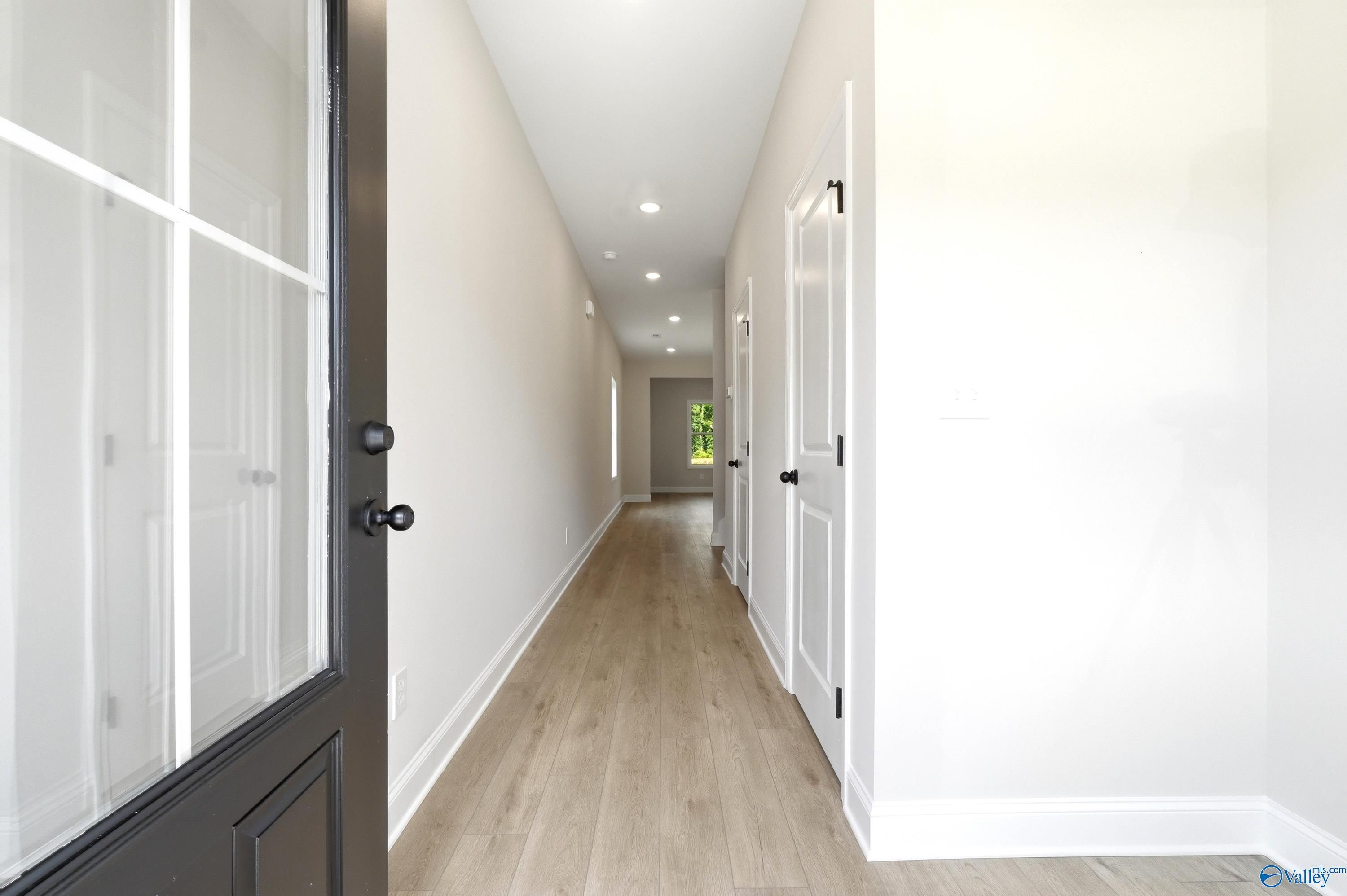 Bright hallway with light wood flooring and white interior doors in The Russell A floor plan, Spragins Cove, Huntsville.