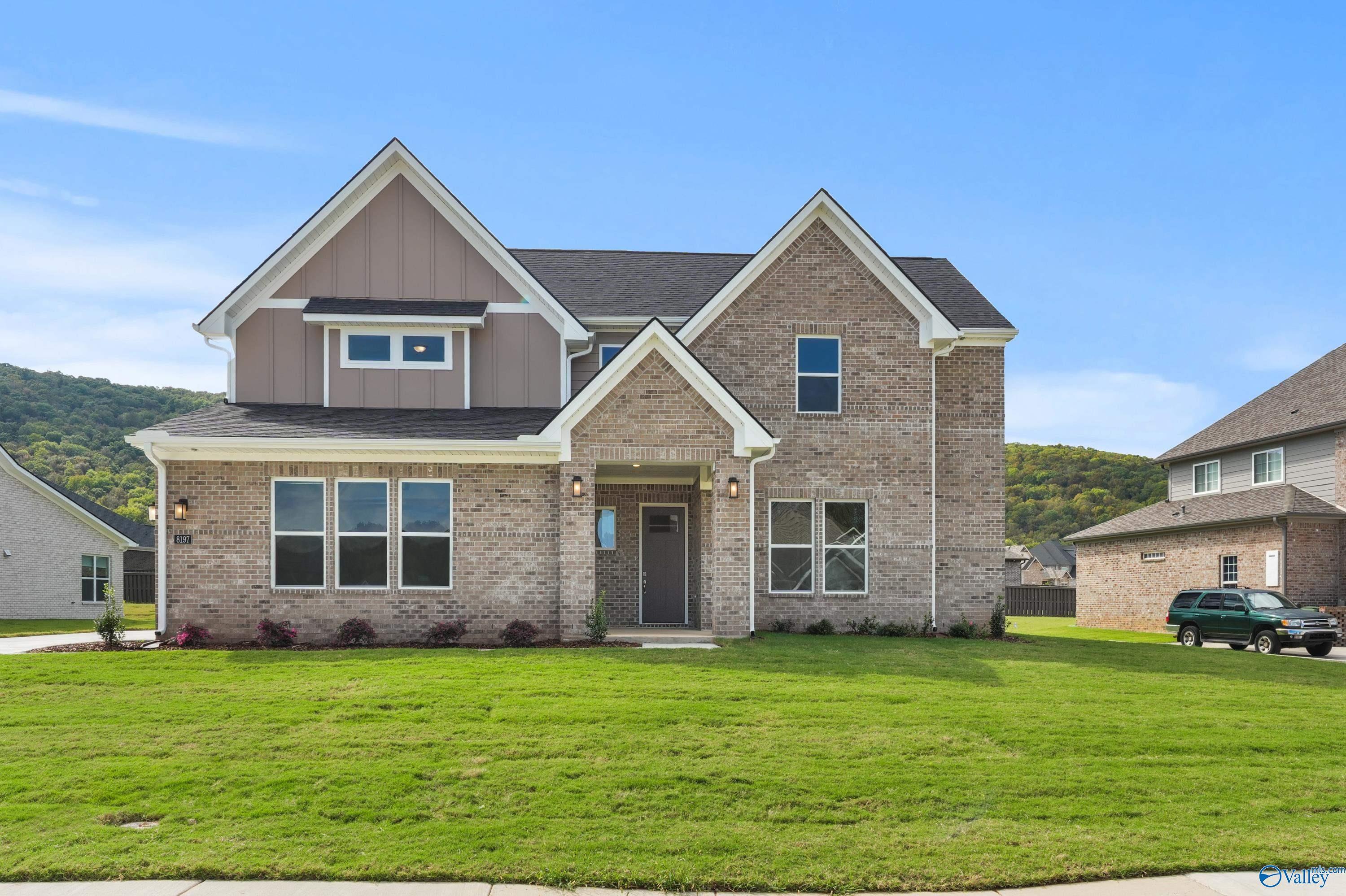 Modern 2-story brick home with gabled roof, 3-car garage, and lush front yard in The Meadows at Hampton Cove, Owens Cross Roads, Alabama