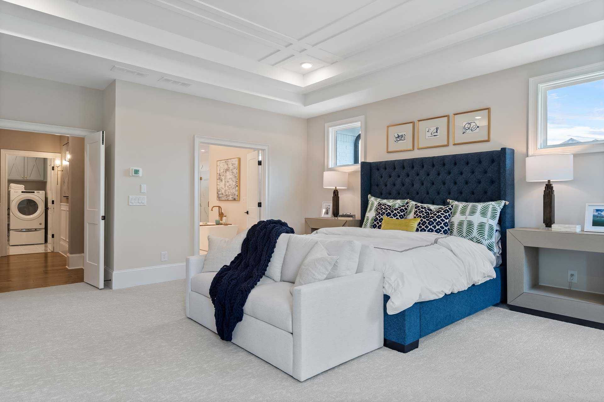 Spacious master bedroom at Tanglewood in East Cobb GA with blue tufted bed, white armchair, and neutral walls