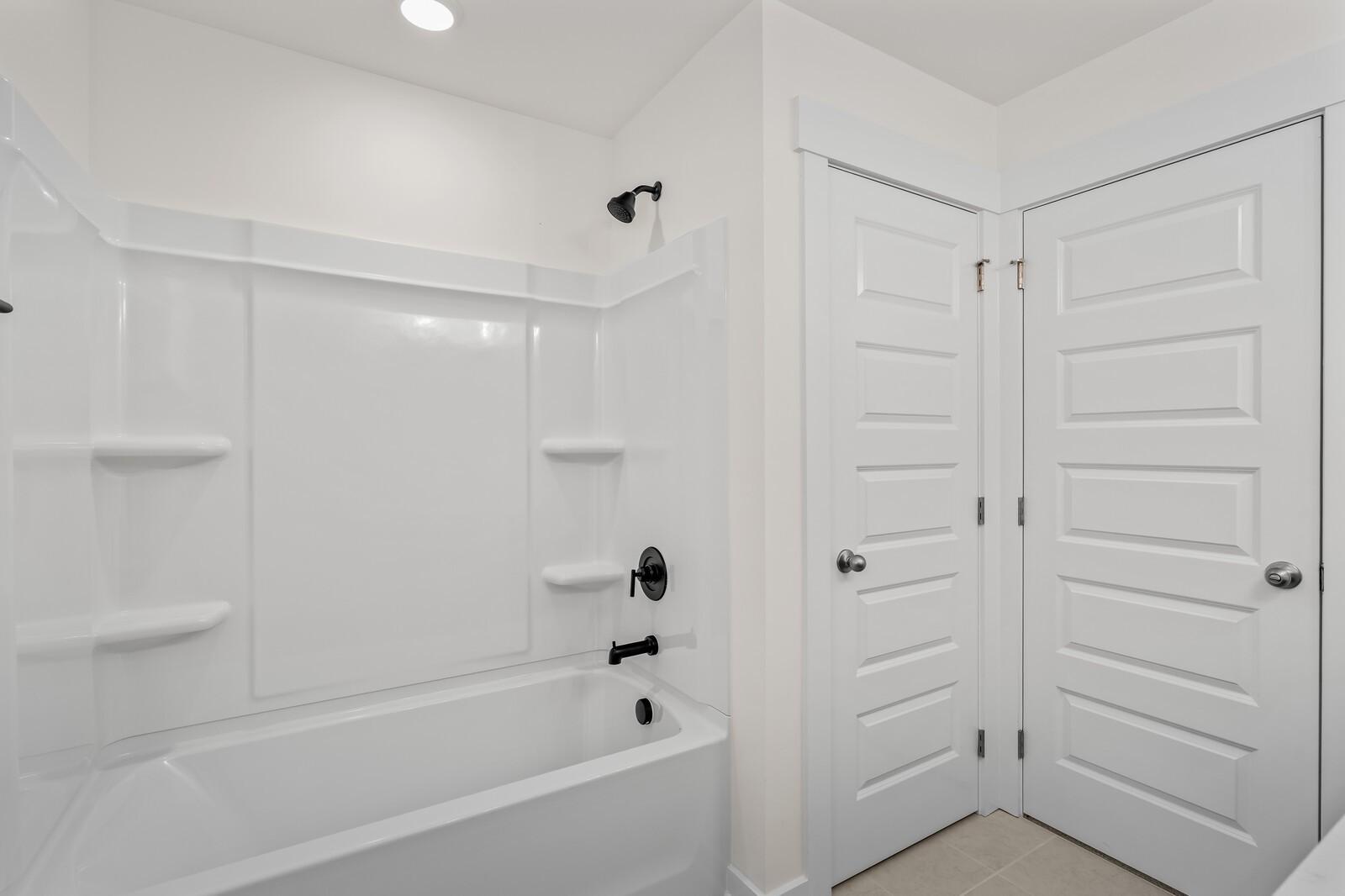 Modern bathroom with white tub-shower combo and black fixtures in a Davidson Homes Willow floor plan in Gallatin, TN.