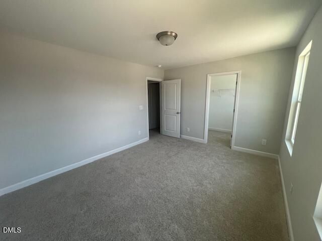 Spacious empty bedroom with gray walls, beige carpet, walk-in closet, and windows in Davidson Homes The Adalynn A, Lillington, NC